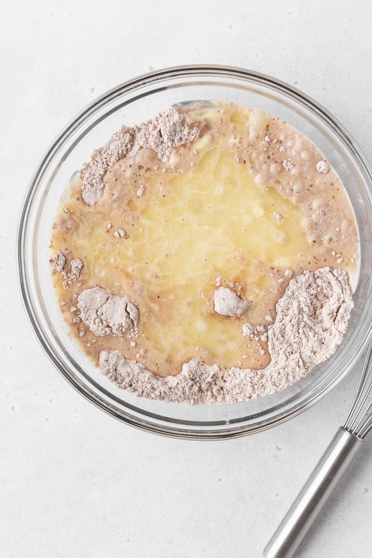 A glass mixing bowl of wet and dry waffle ingredients before mixing.