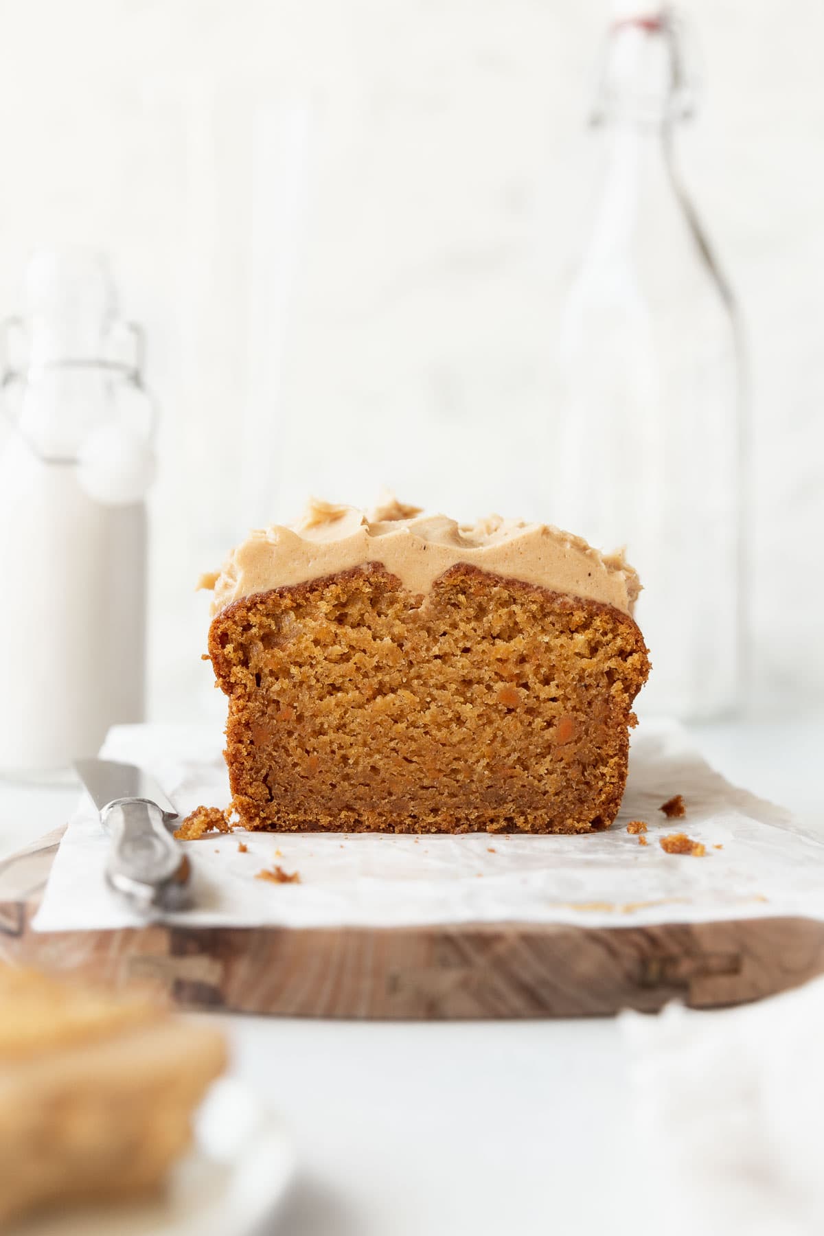Straight on shot of sweet potato cake with cashew frosting on parchment paper over a wooden board.