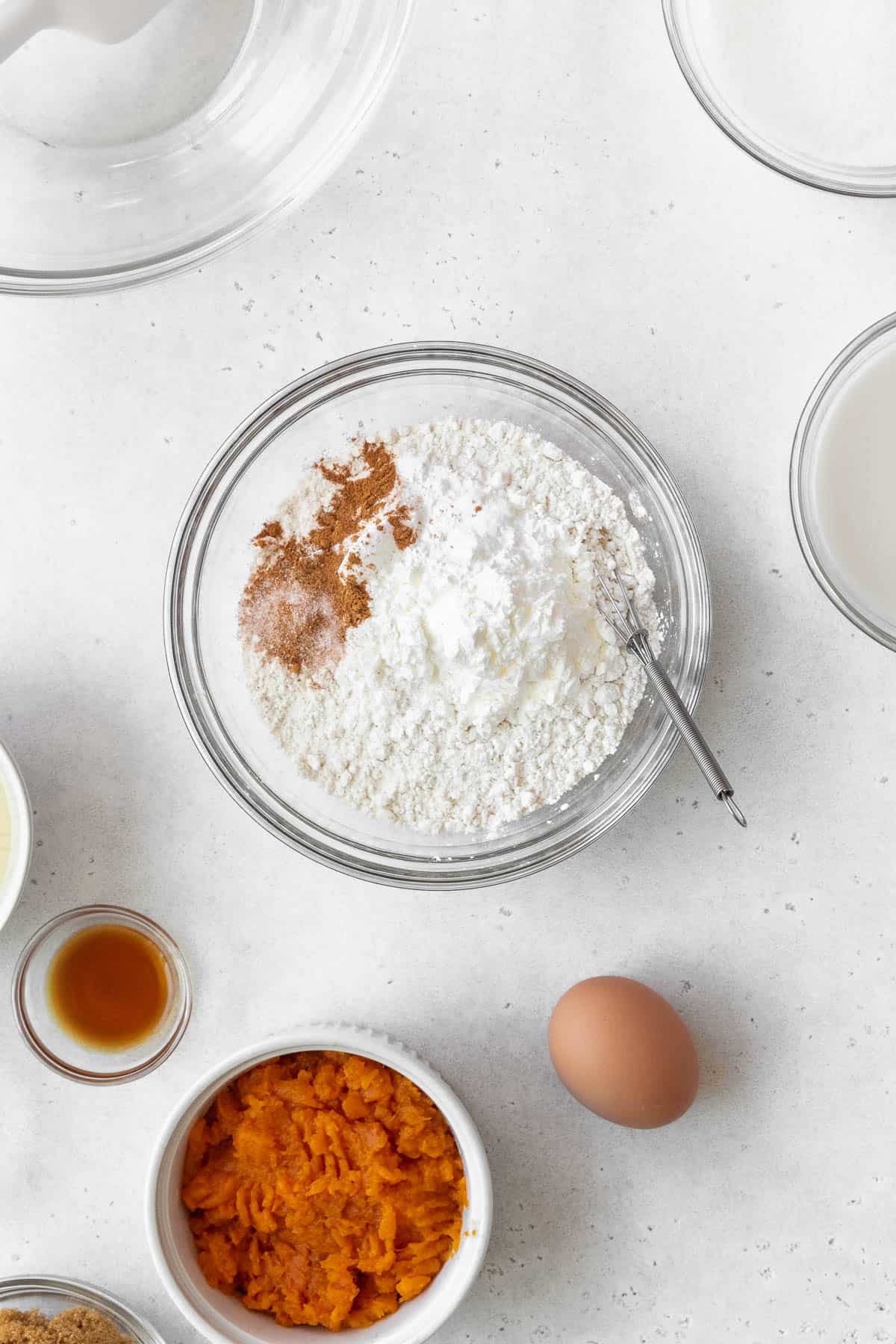 Flour, salt, baking soda, baking powder, and spices in a glass bowl ready to be mixed.