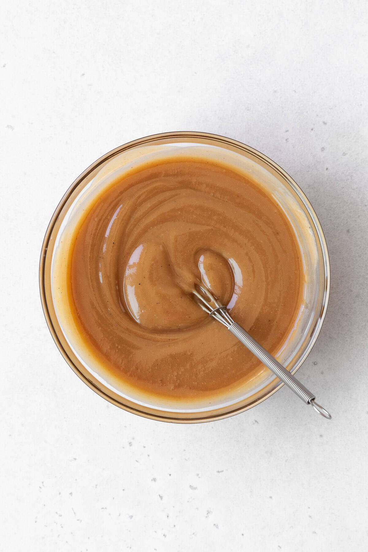A bowl of maple cashew frosting ingredients mixed together in a glass bowl.