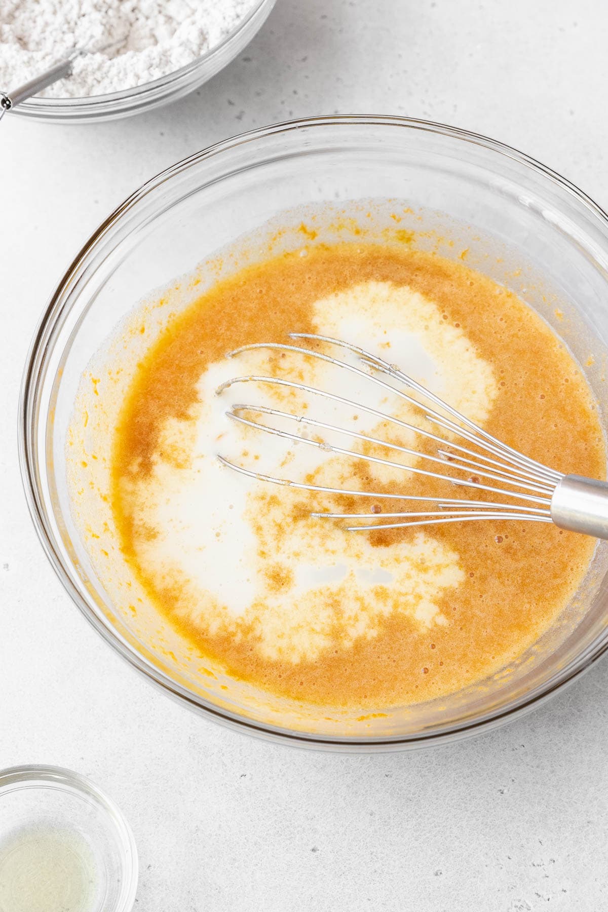 Non-dairy milk whisked into the glass bowl of wet ingredients.
