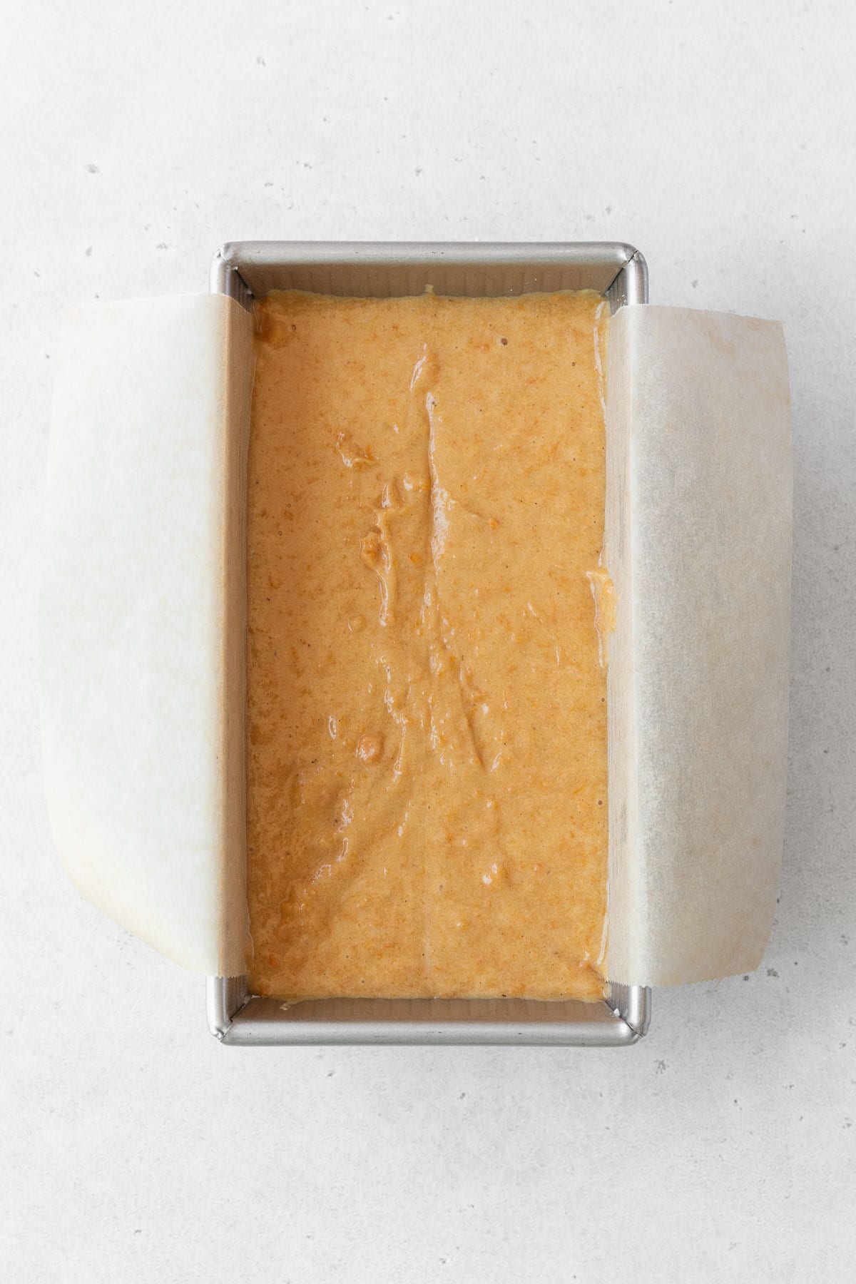 Gluten free sweet potato loaf in a metal loaf pan lined with parchment paper.