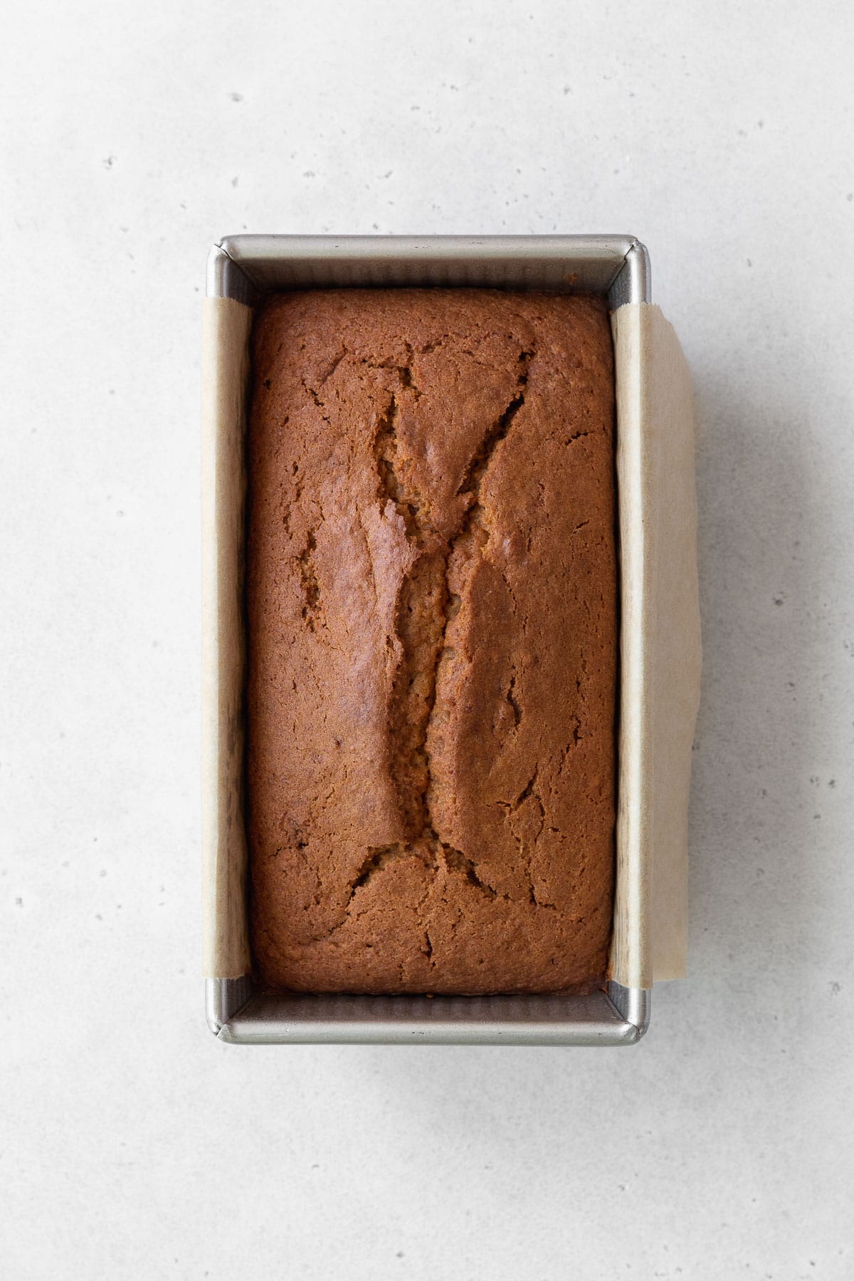 Overhead shot of a baked sweet potato loaf cake in a metallic pan.
