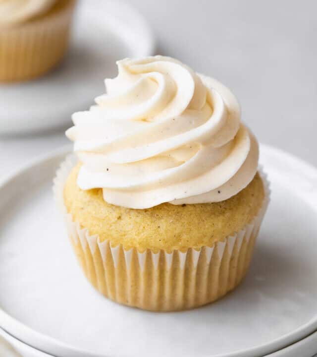 45 degree angle shot of dairy-free vegan frosting piped into a high swirl on homemade vanilla bean cupcakes.