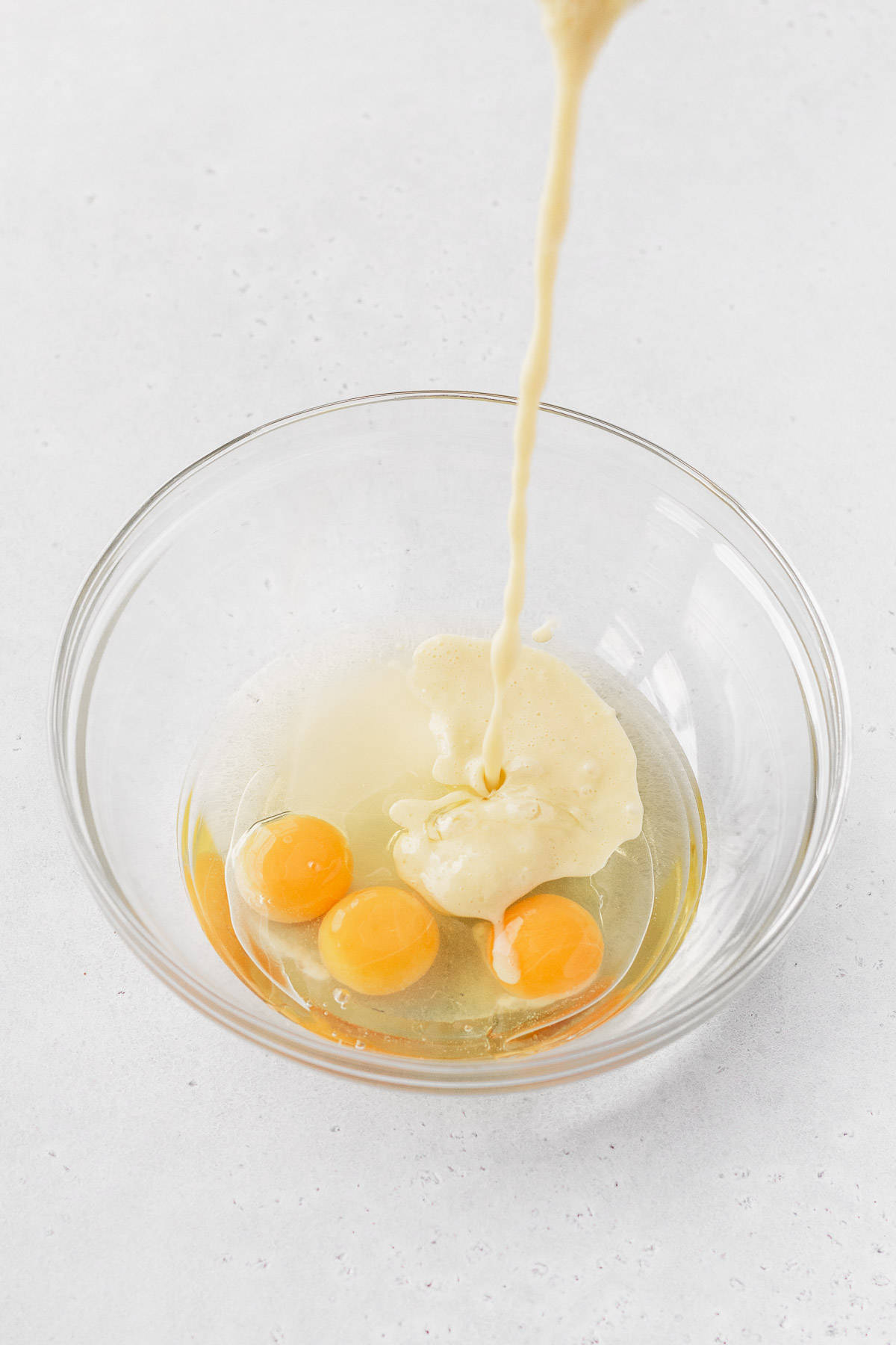 Pouring the milk into the mixing bowl with eggs.