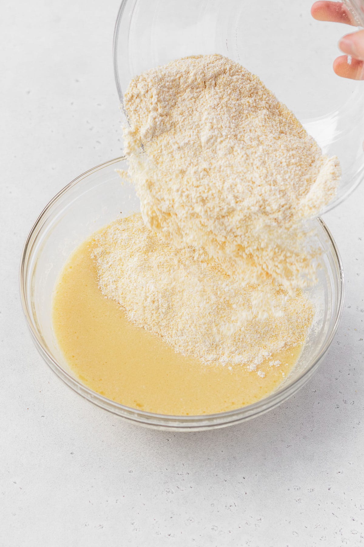 Pouring the dry ingredients into the wet cornbread ingredients.