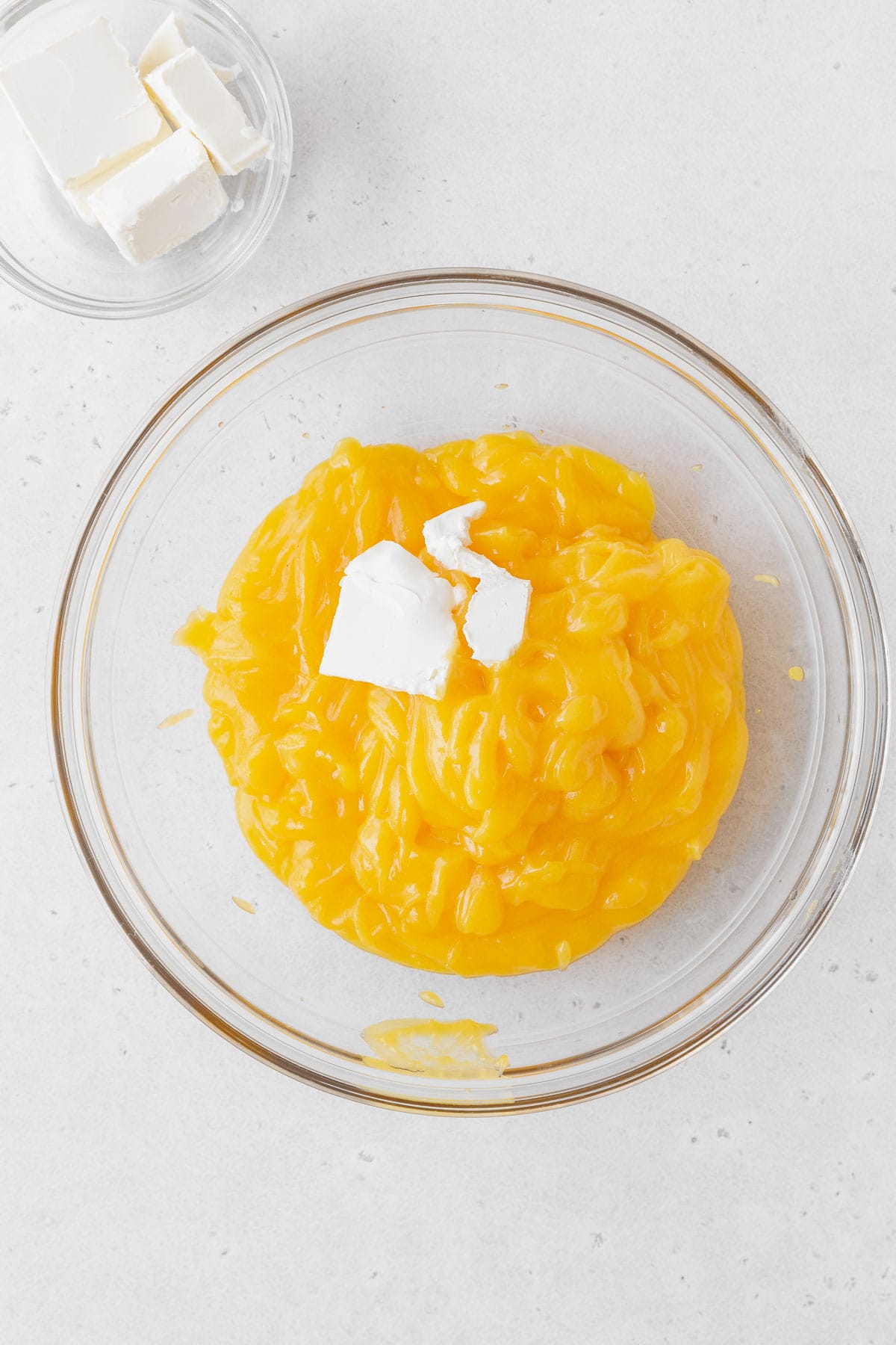 Adding butter to the bowl of lemon curd.