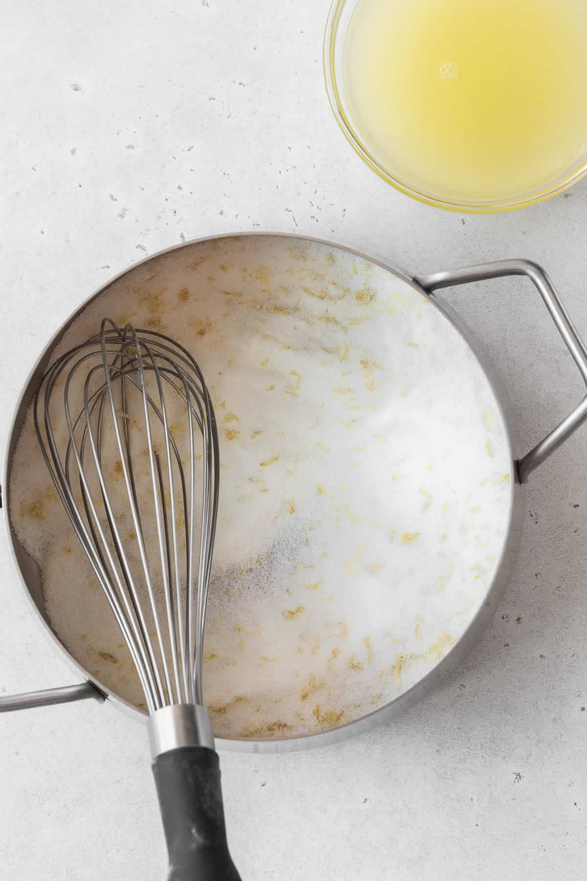 Whisked sugar and lemon zest in a pan on the counter.