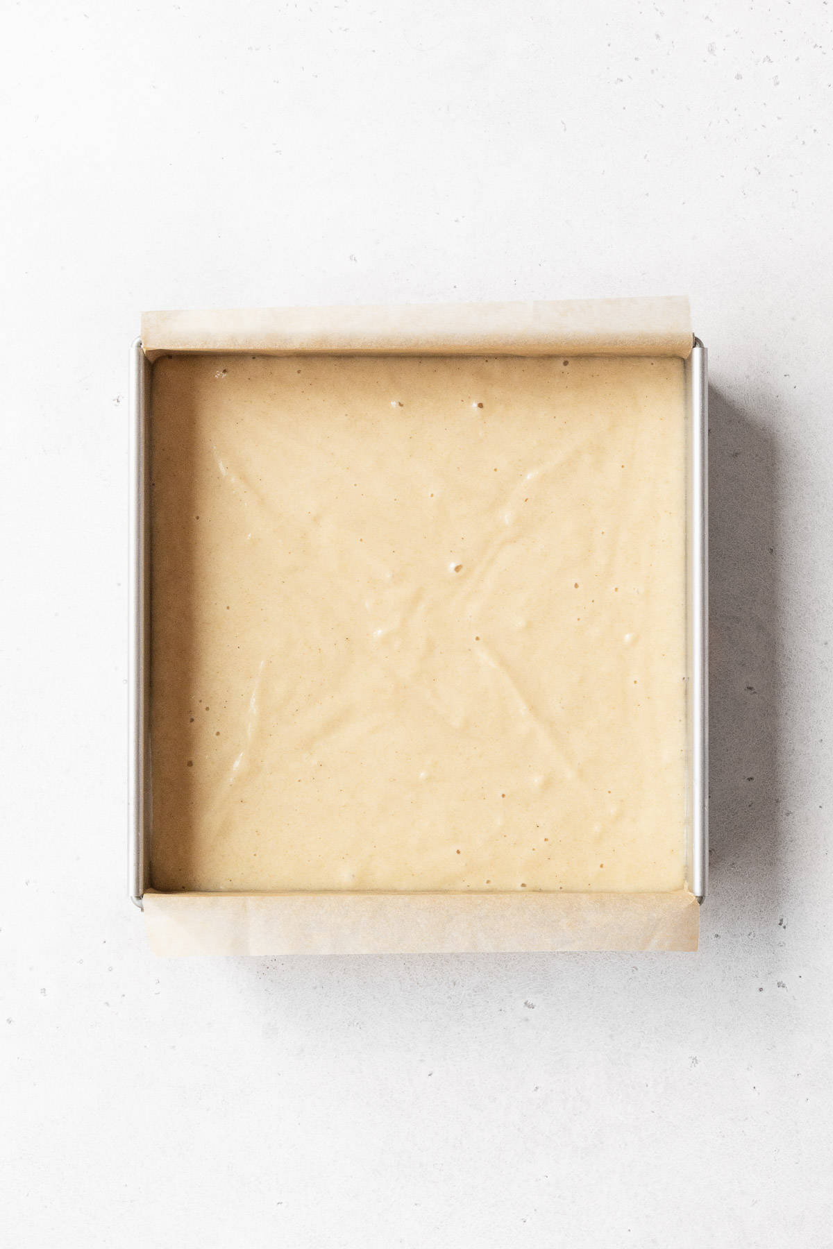An 8x8-inch baking pan of the gluten-free and dairy-free tres leches cake before baking.