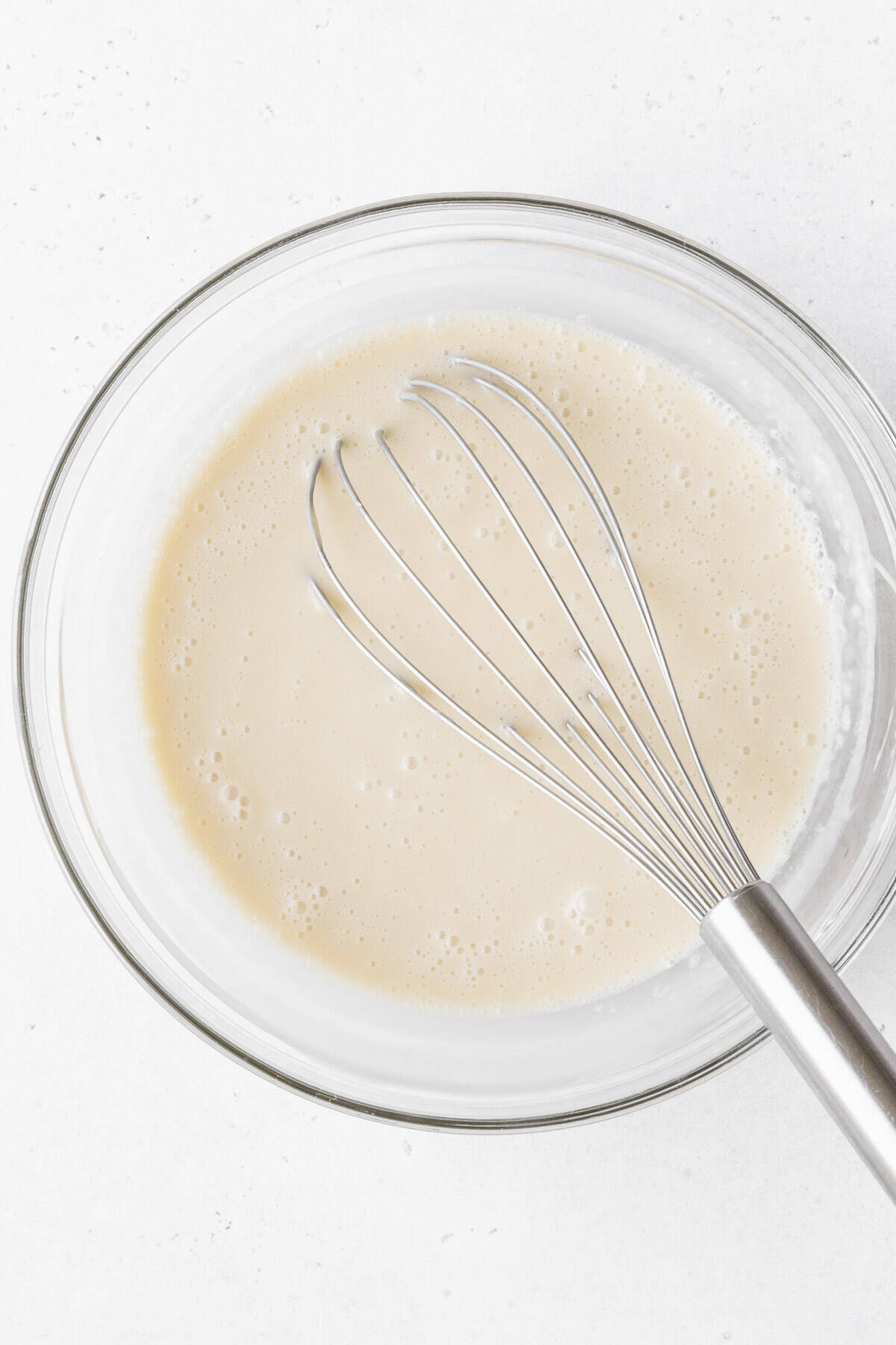 The gluten-free and dairy-free tres leches milk soak mixed together in a glass mixing bowl.