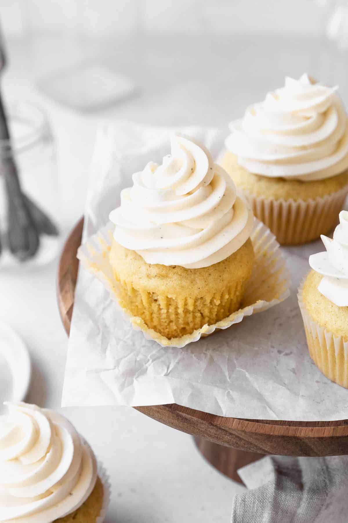 A dairy-free vanilla cupcake with the wrapper pulled off to expose the texture of the cake.