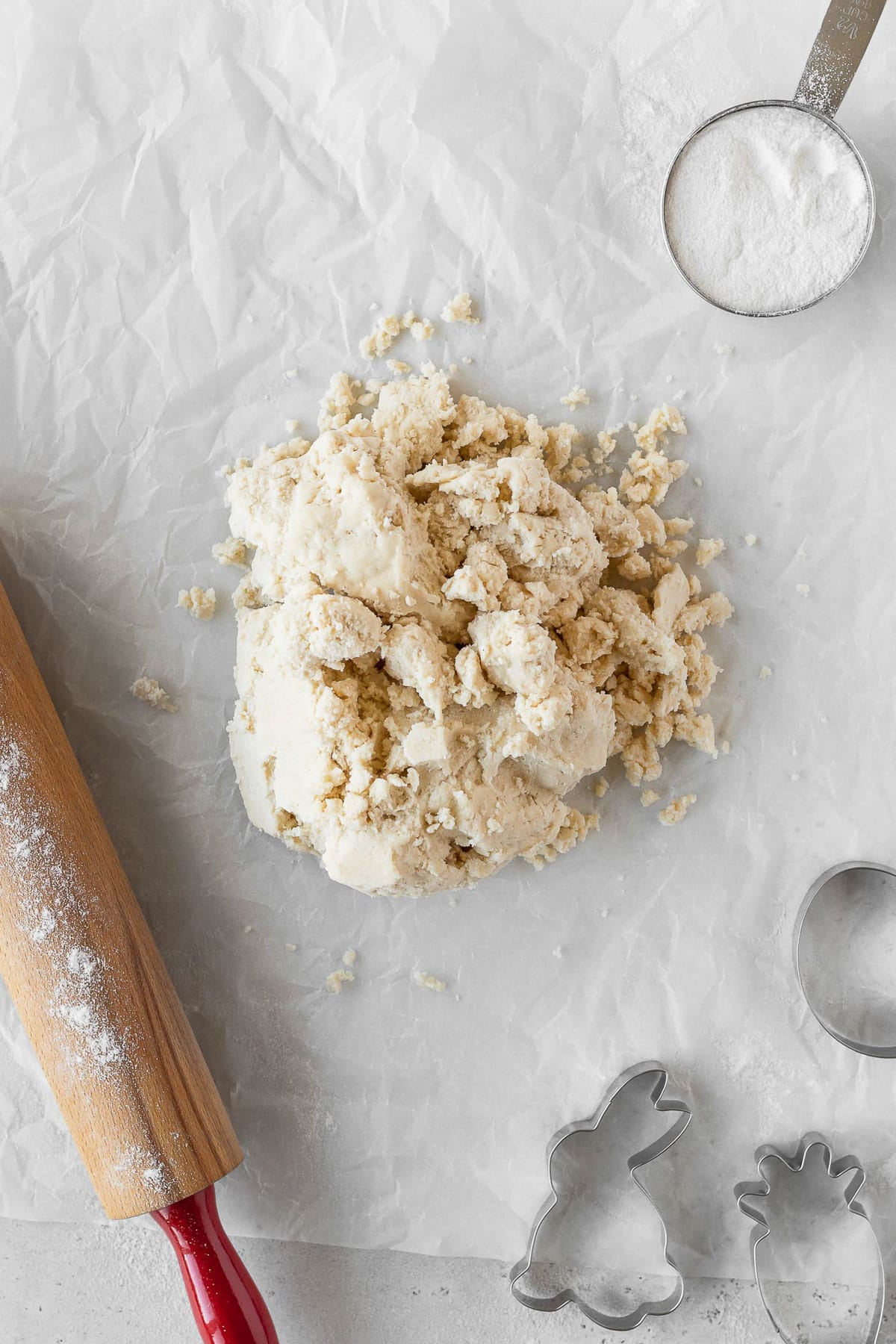 Cookie dough on parchment paper with some cookie cutters.