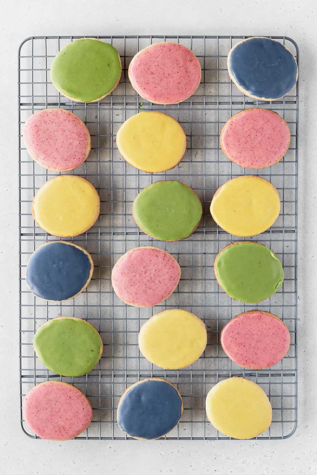 Blue, green, yellow, and pink vegan cookie icing in small bowls.