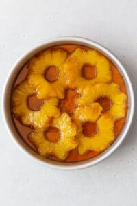 A cake pan of the brown sugar butter and pineapple rings in it.