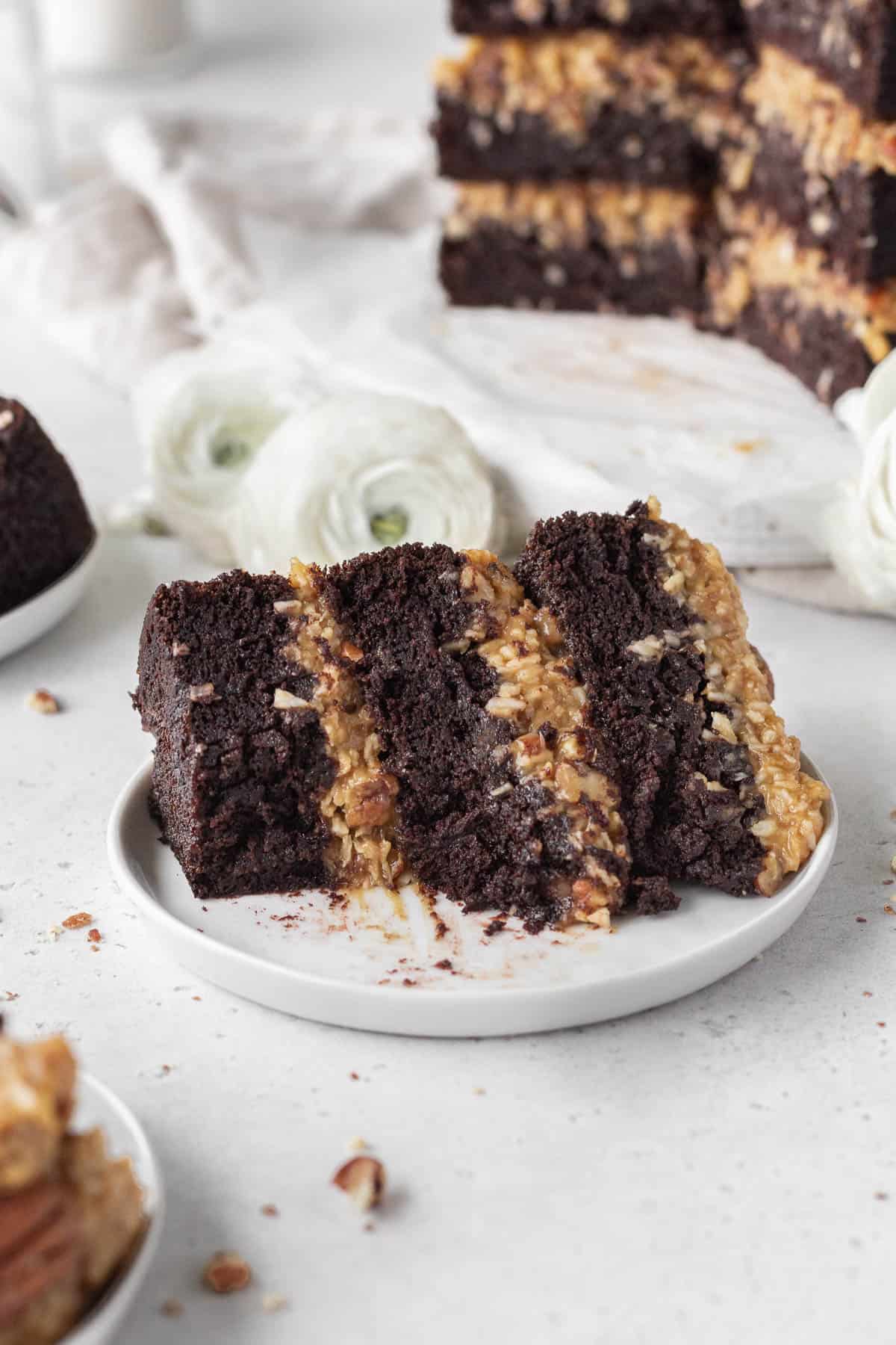 A slice of gluten-free dairy-free German chocolate cake on a white plate with a bite taken out.
