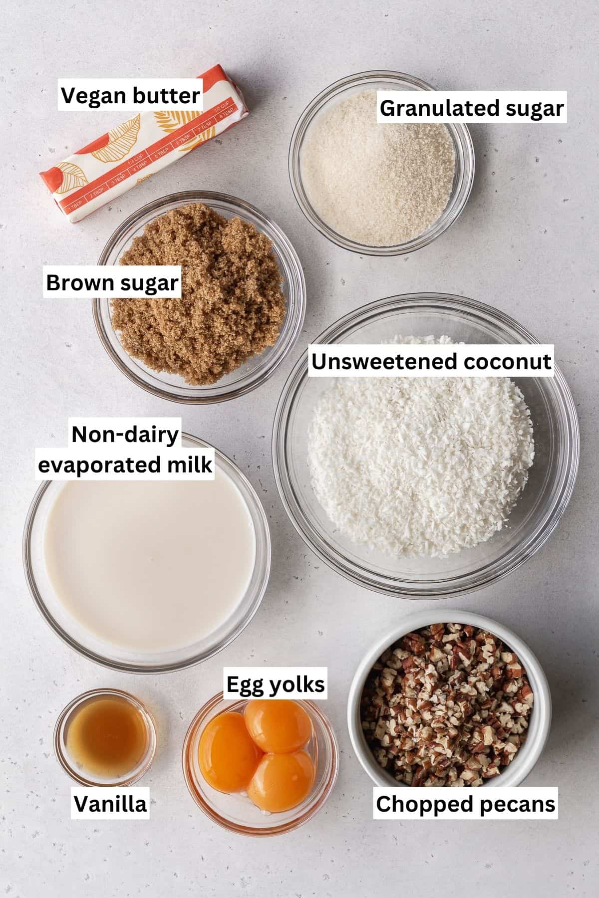 German chocolate frosting ingredients measured out into bowls and placed on a grey surface with text overlay.