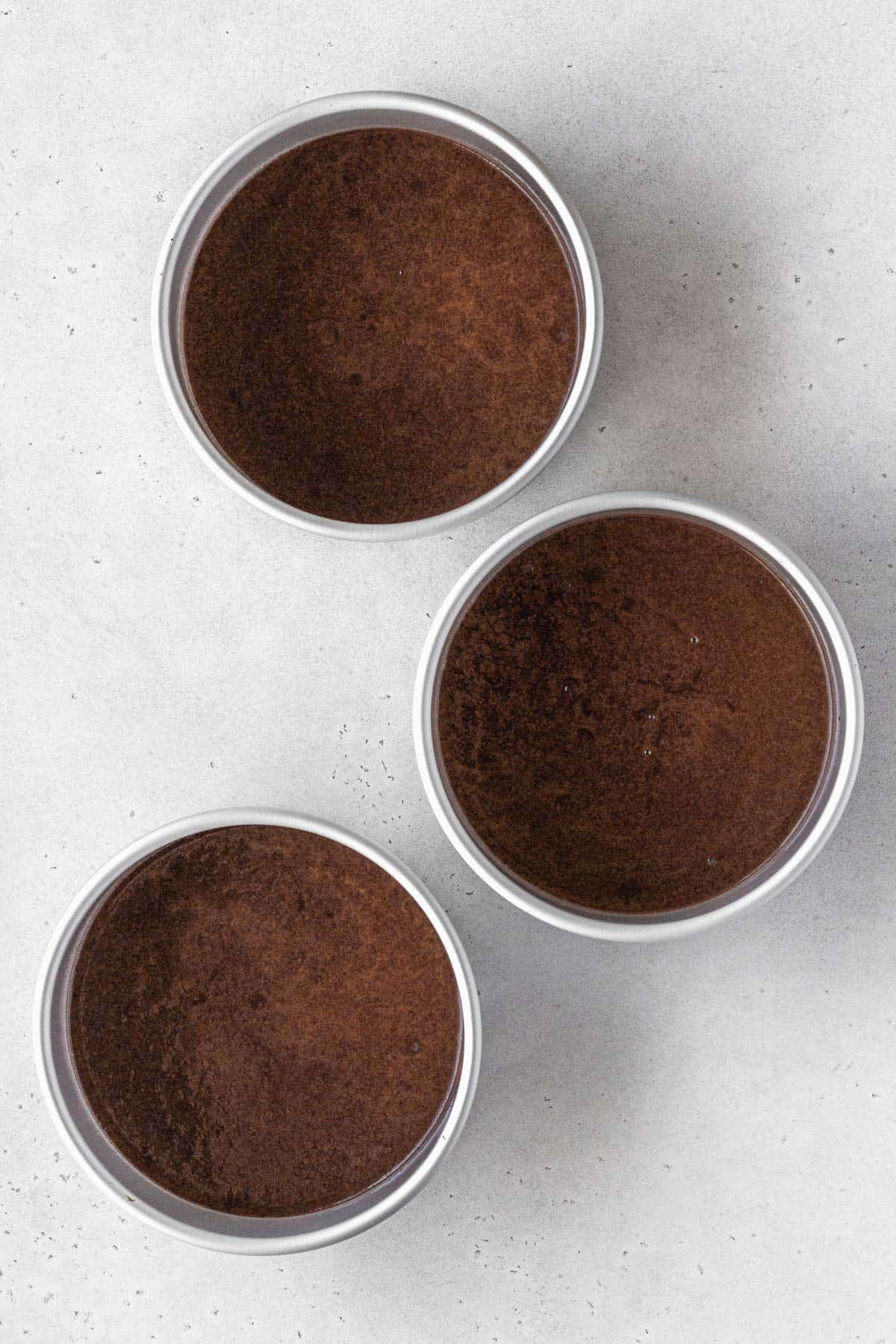 German chocolate cake batter in three 6 inch round cake pans.