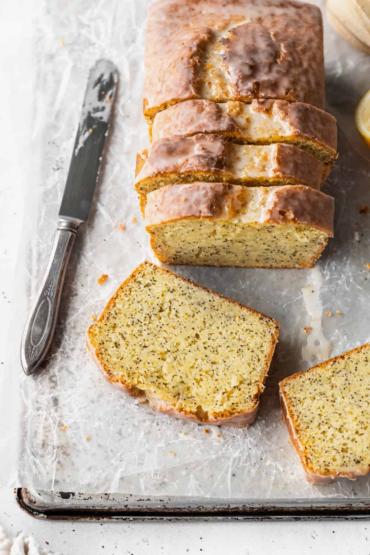 Overhead shot of a sliced lemon poppysead loaf with two slices laying in front of it.
