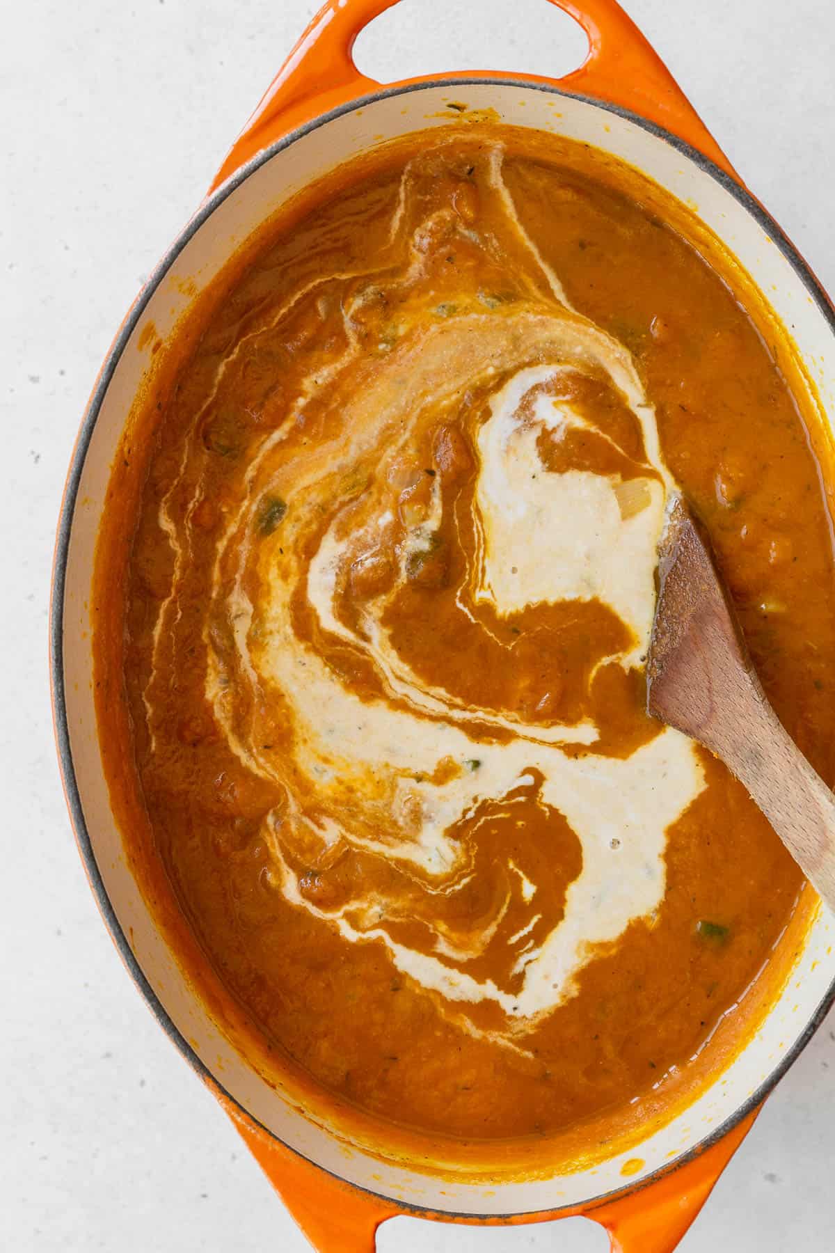 Coconut milk added to the pot with the rest of the vegan pumpkin soup ingredients.