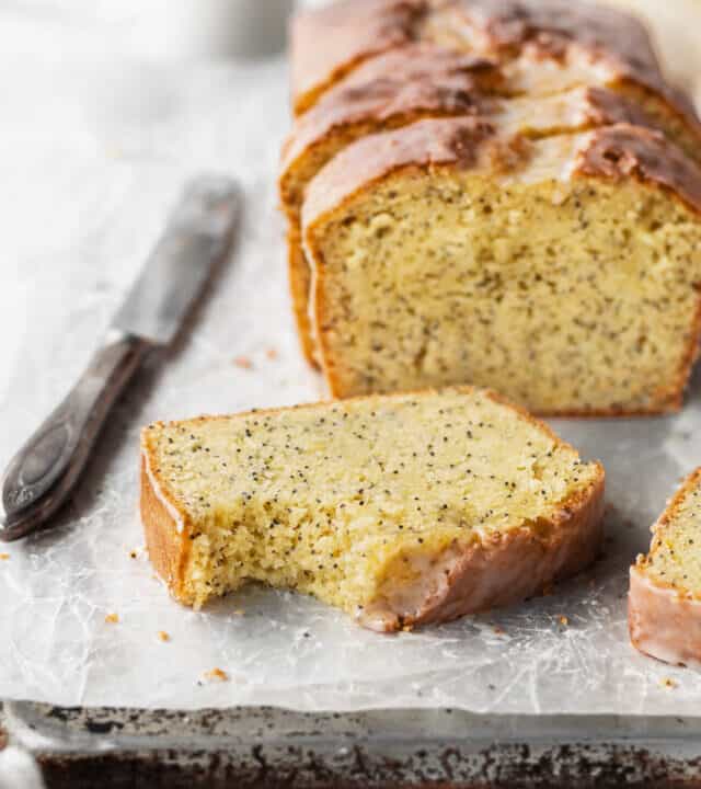 A bitten slice of gluten free lemon bread with the loaf in the background.