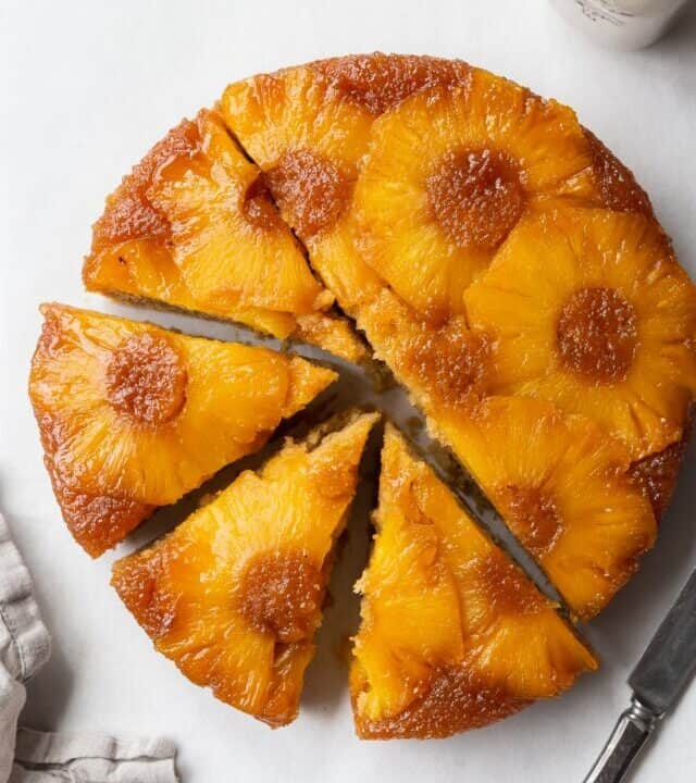 Sliced gluten-free pineapple upside down cake on the counter with a napkin and knife.