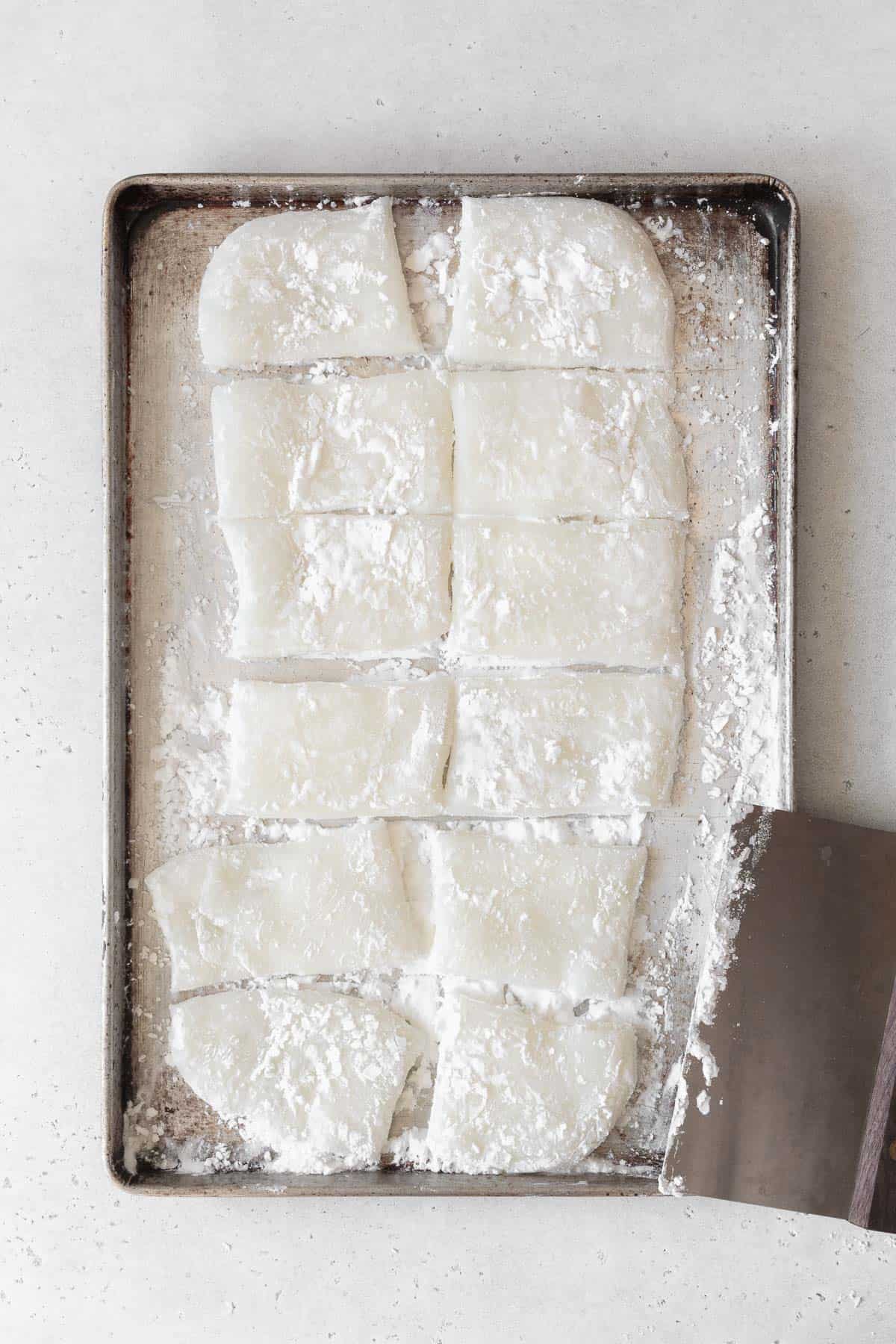 Mochi cut into 12 pieces using a bench scraper.