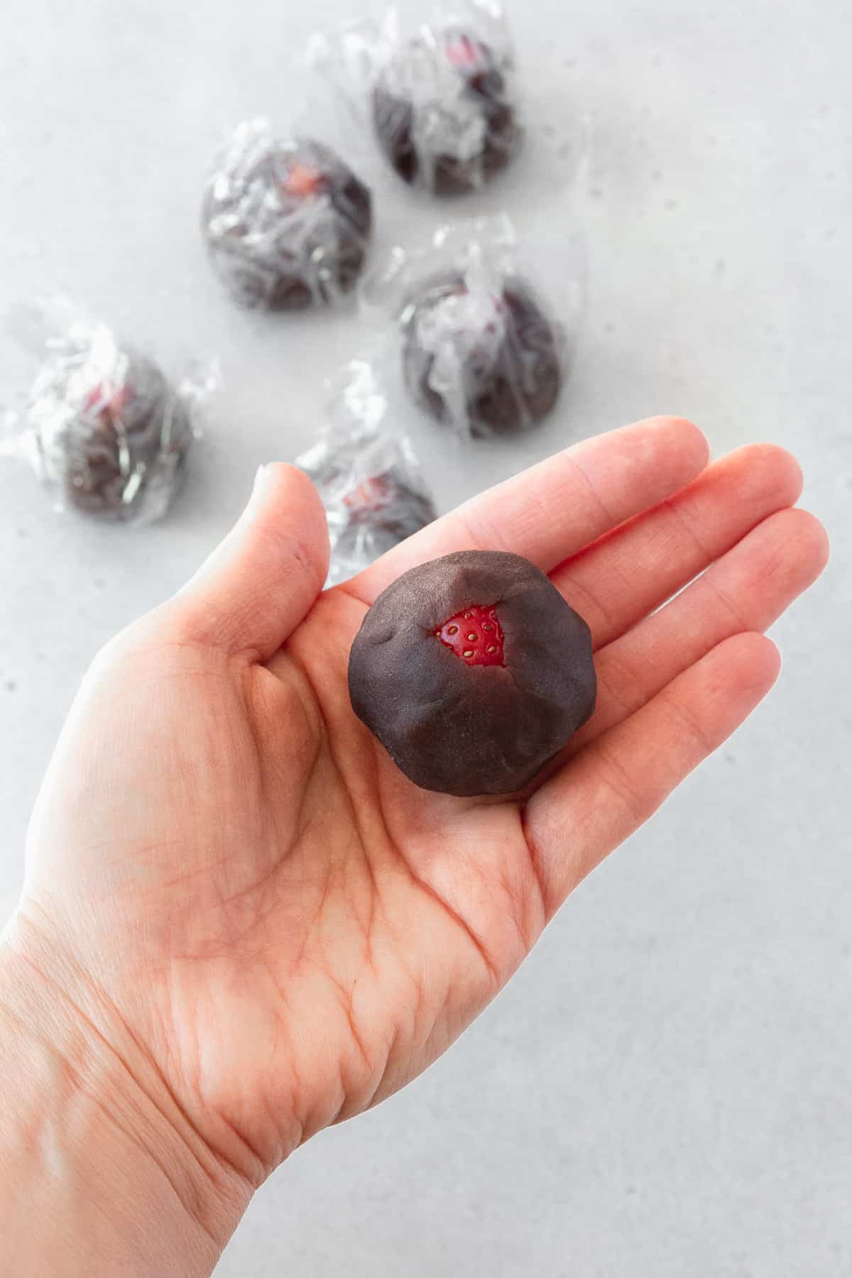 A strawberry wrapped in anko on the palm of a hand.