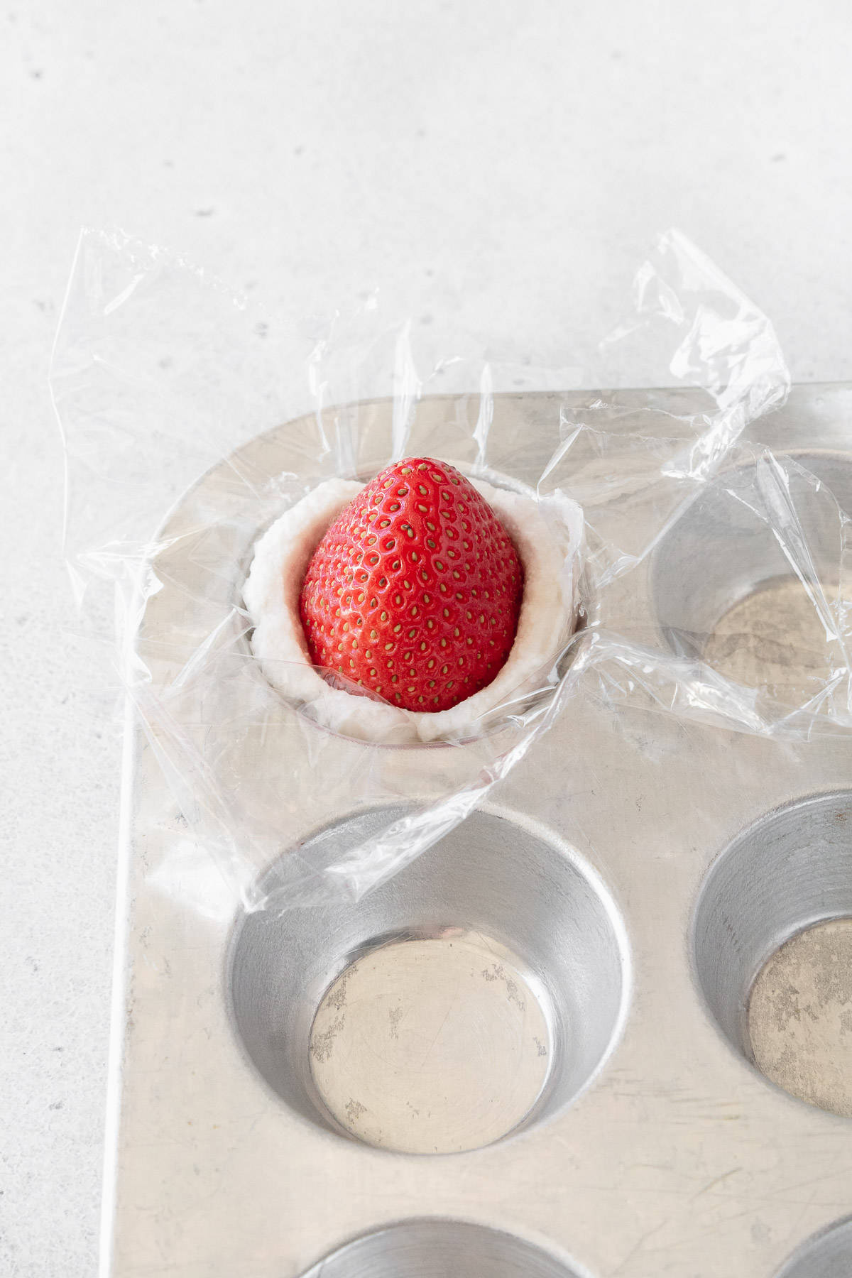 A strawberry put into a portion of whipped cream with the tip of the strawberry pointing up.