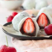 A sliced strawberry mochi on a black plate.
