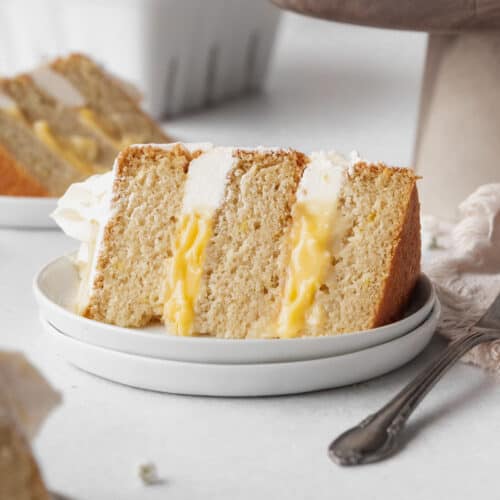 Square hero shot of a slice of lemon curd cake on a white dessert plate.