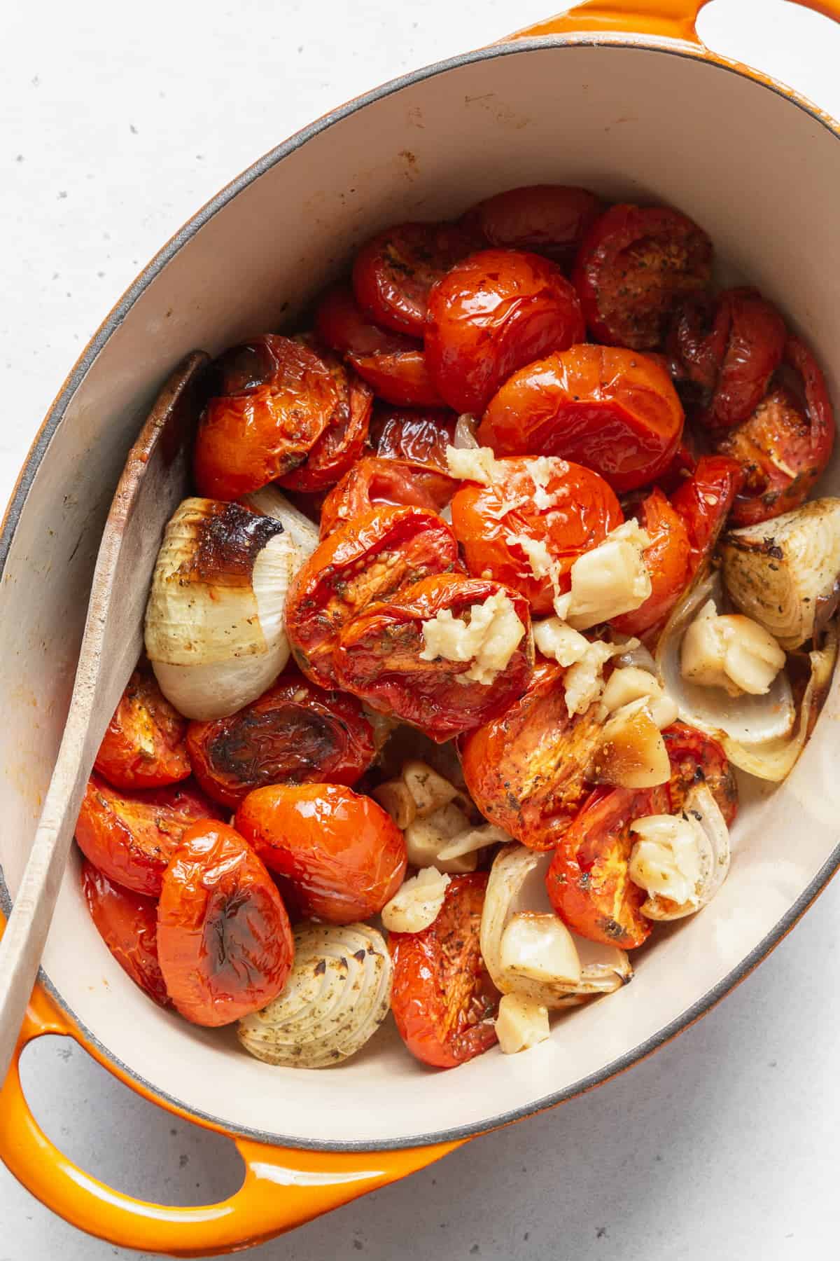 A large pot full of roasted tomatoes, onions, and garlic.