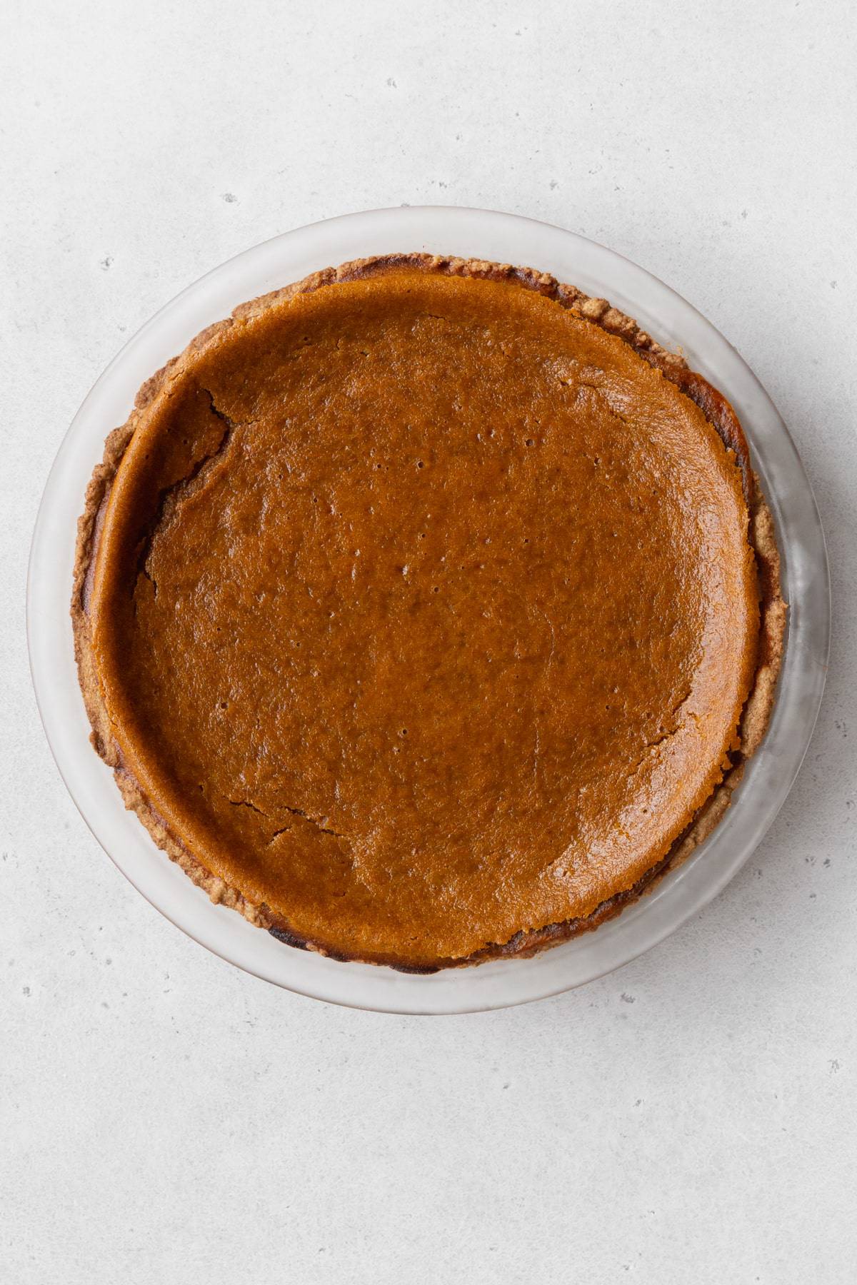 Baked vegan pumpkin pie on a white surface.