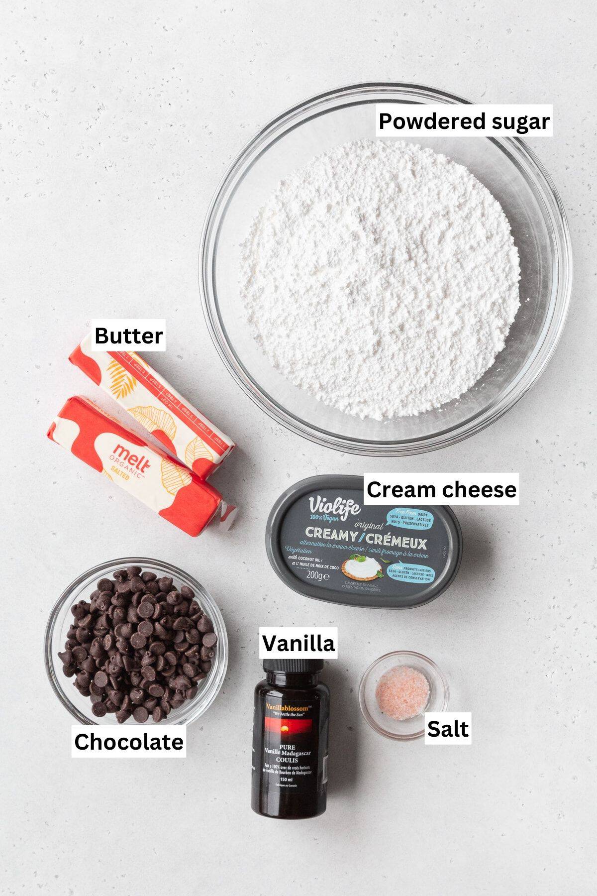 Ingredients for chocolate cream cheese frosting on a white surface.
