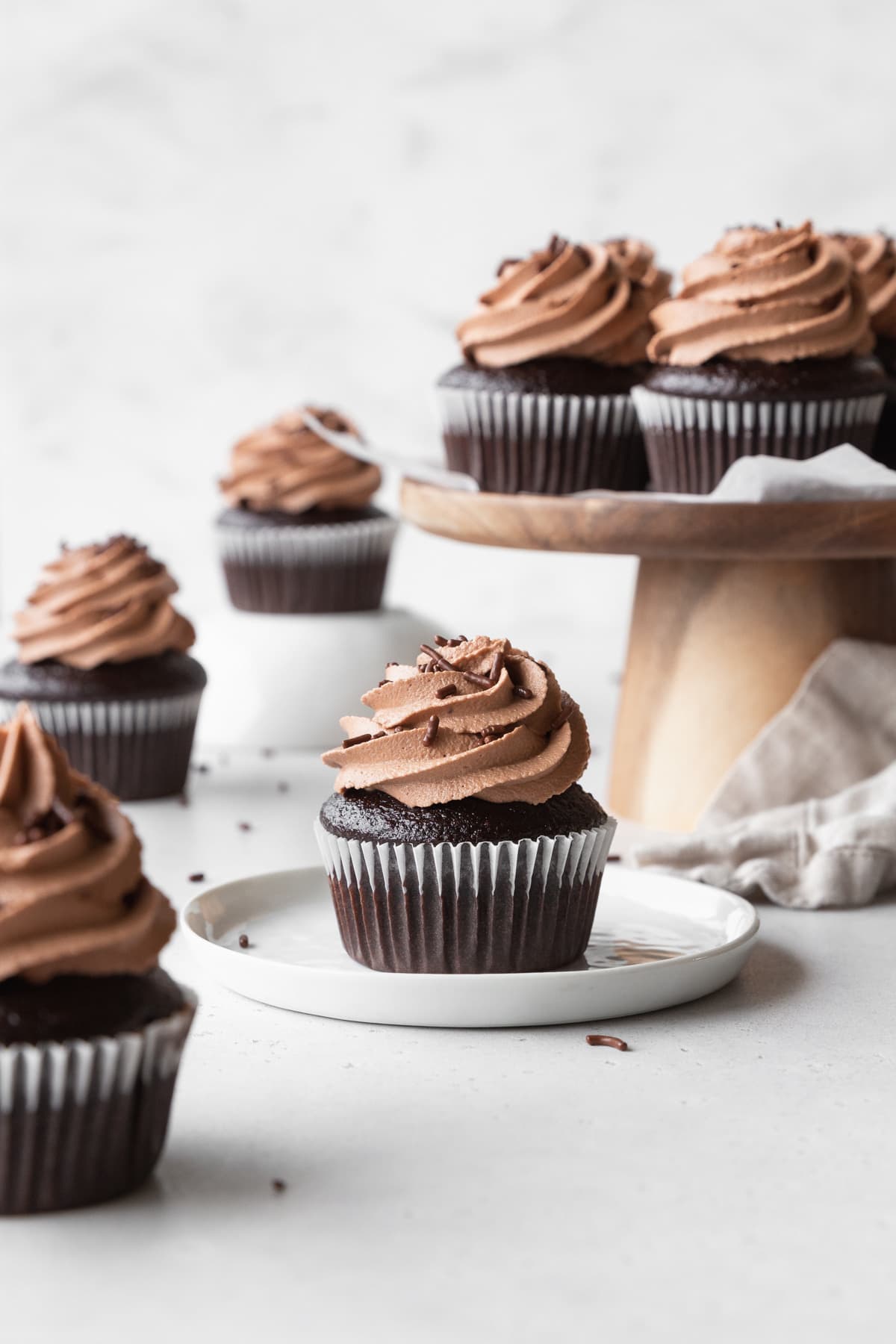 Chocolate cupcakes with chocolate cream cheese frosting scattered around.