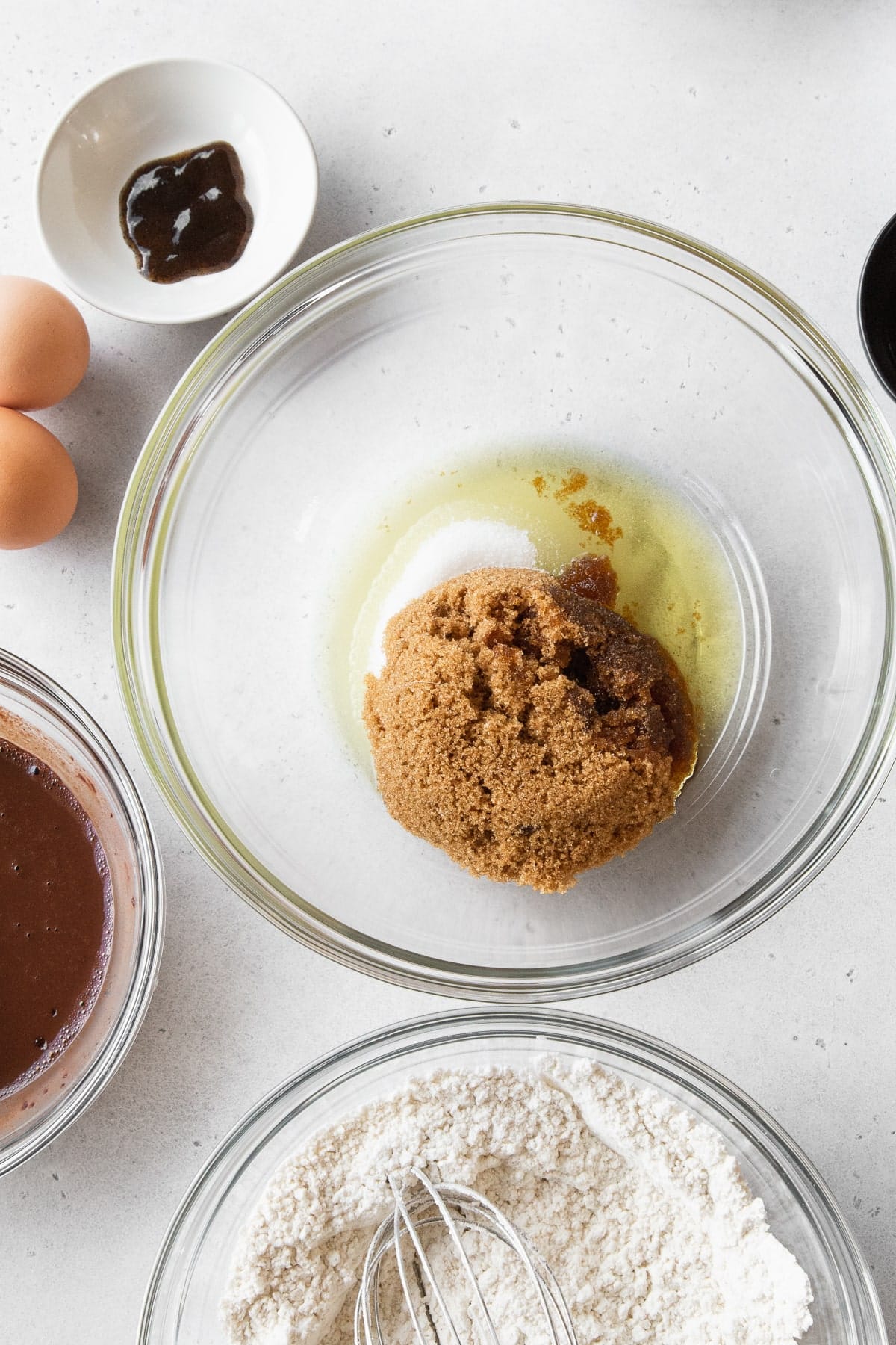 Brown sugar, granulated sugar, and oil in a glass bowl.