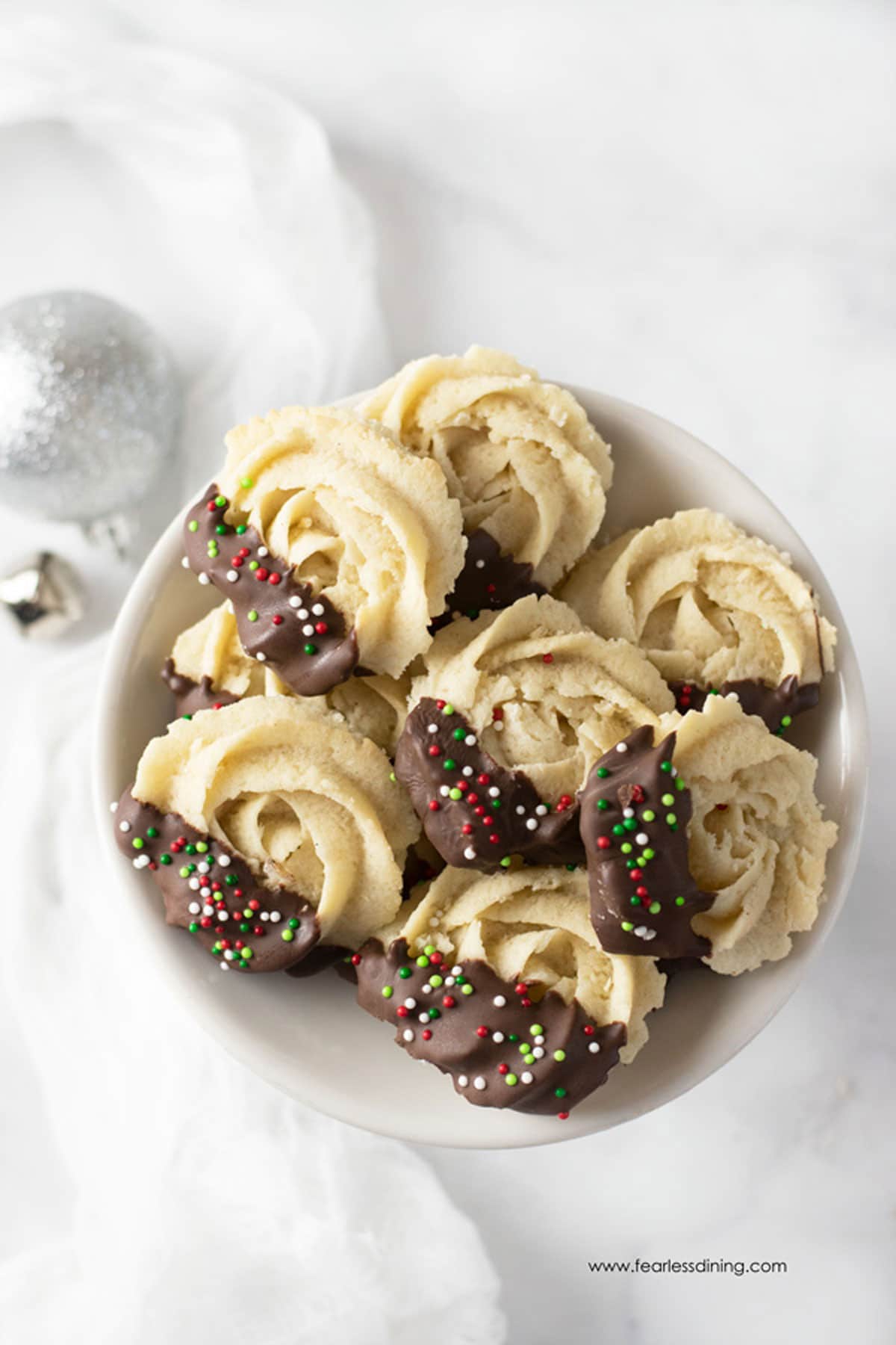 A plate of Danish butter cookies dipped in chocolate with some Christmas sprinkles.