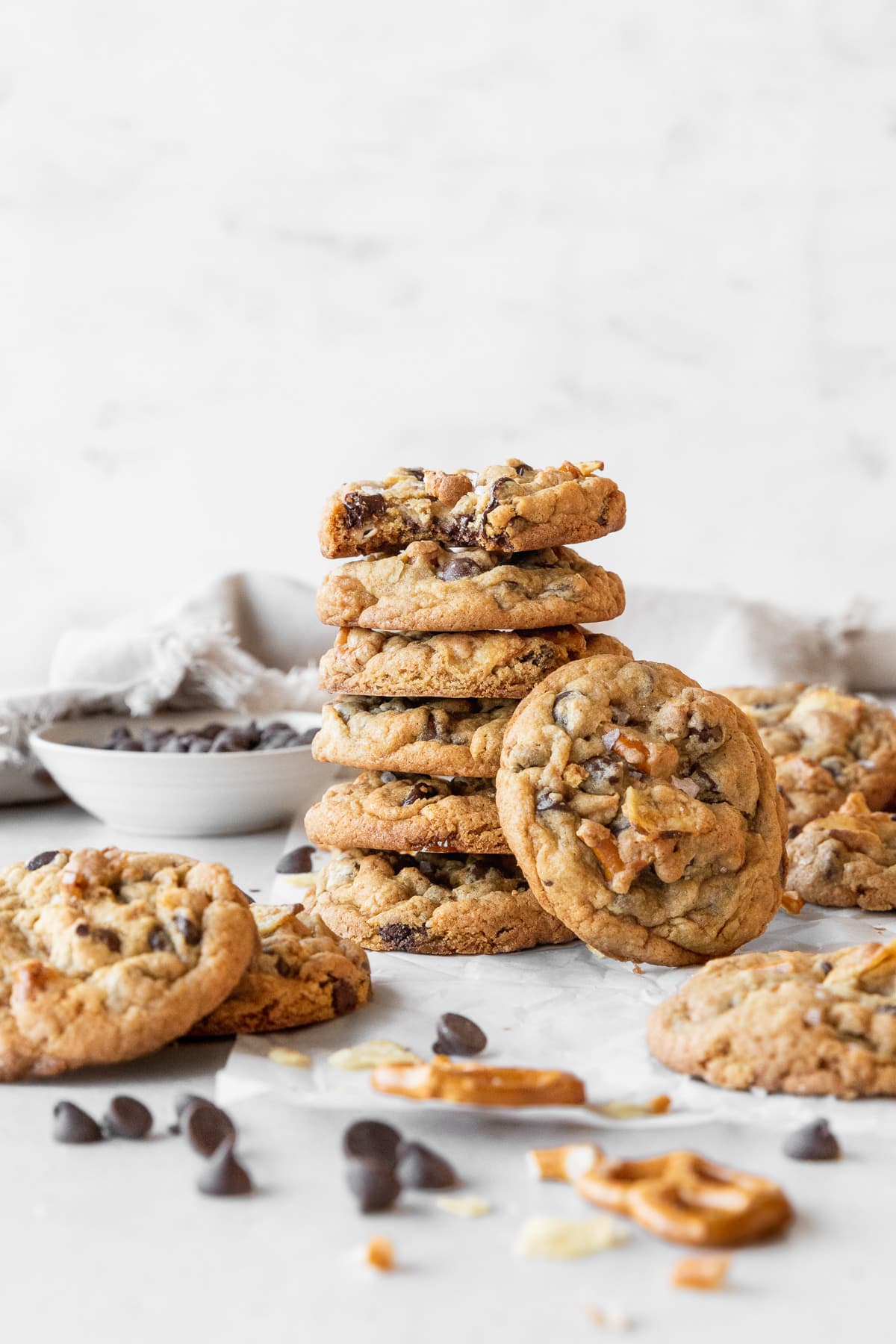 A stack of kitchen sink cookies on a light grey surface surrounded by more cookies.