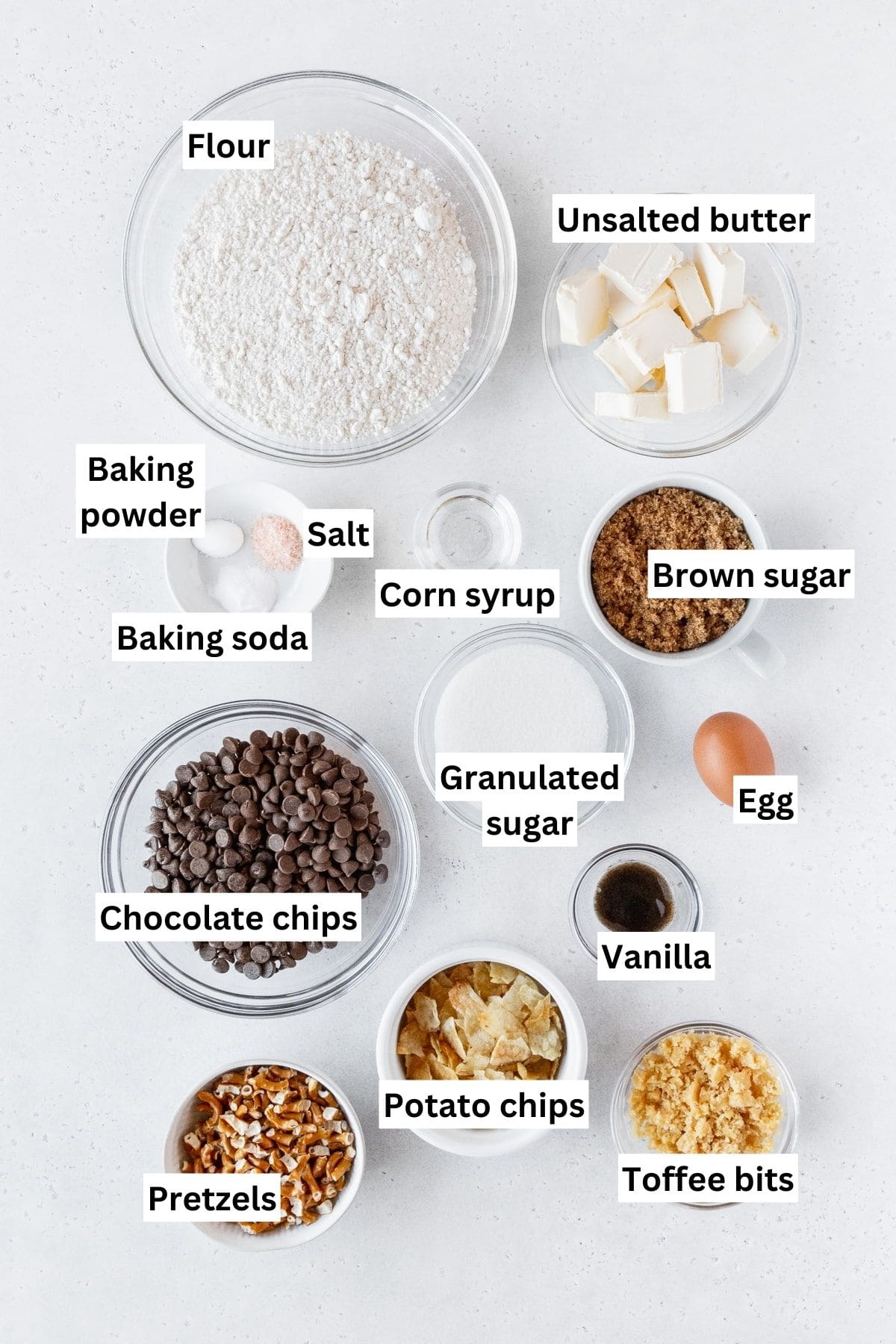 Kitchen sink cookie ingredients measured out into bowls on a white surface with text overlay.