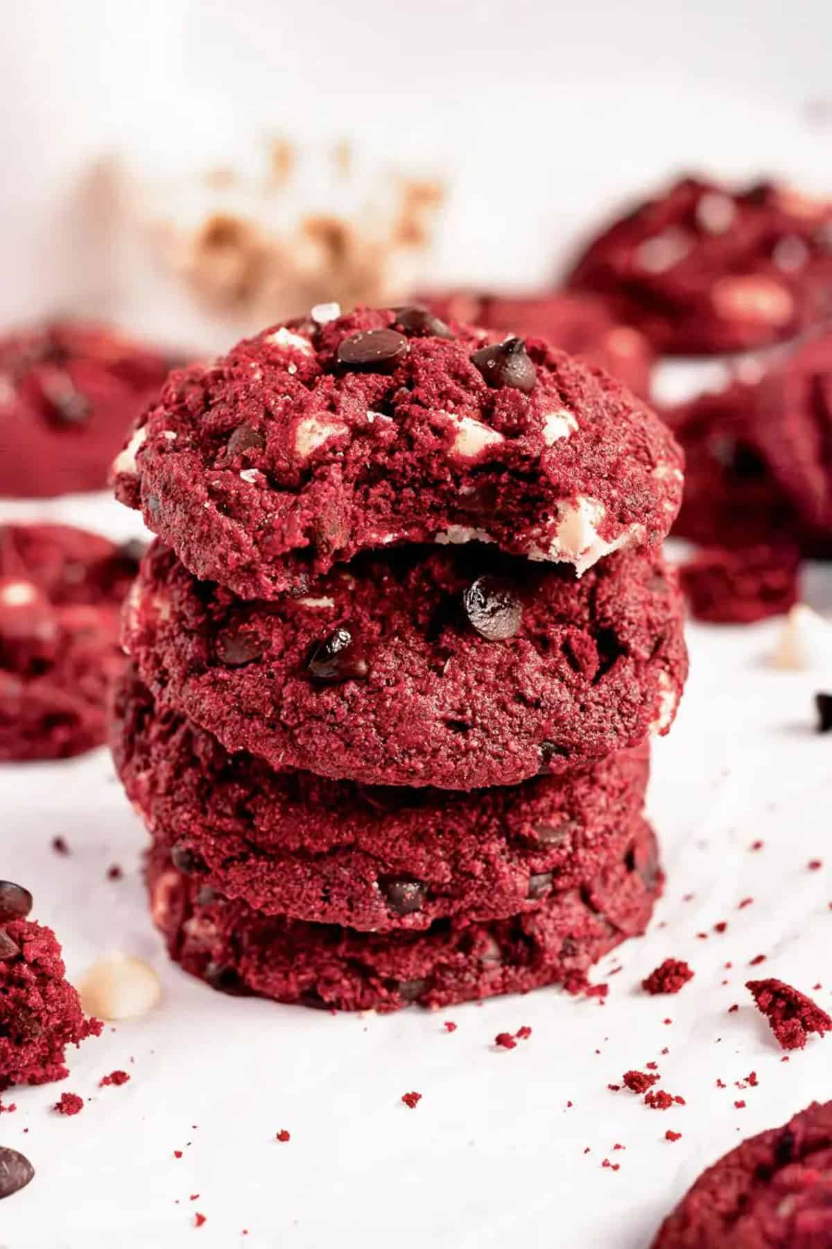 A stack of vegan red velvet cookies, with the top one having been bitten into.
