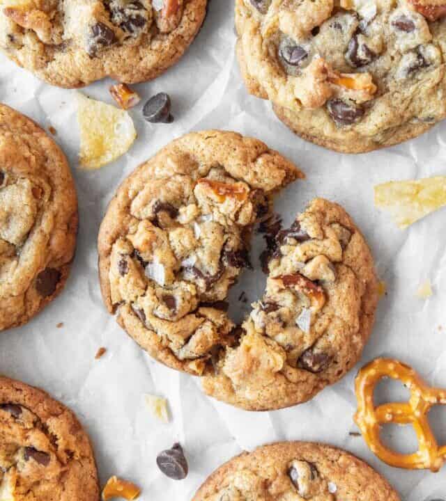 A everything but the kitchen sink cookie broken in half with more cookies scattered around.