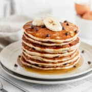 A stack of gluten free banana pancakes drizzled with maple syrup.