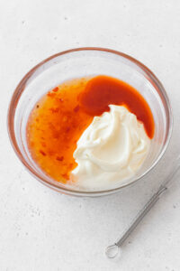 Mayo, sweet chili sauce, sriracha, and rice vinegar in a glass bowl.