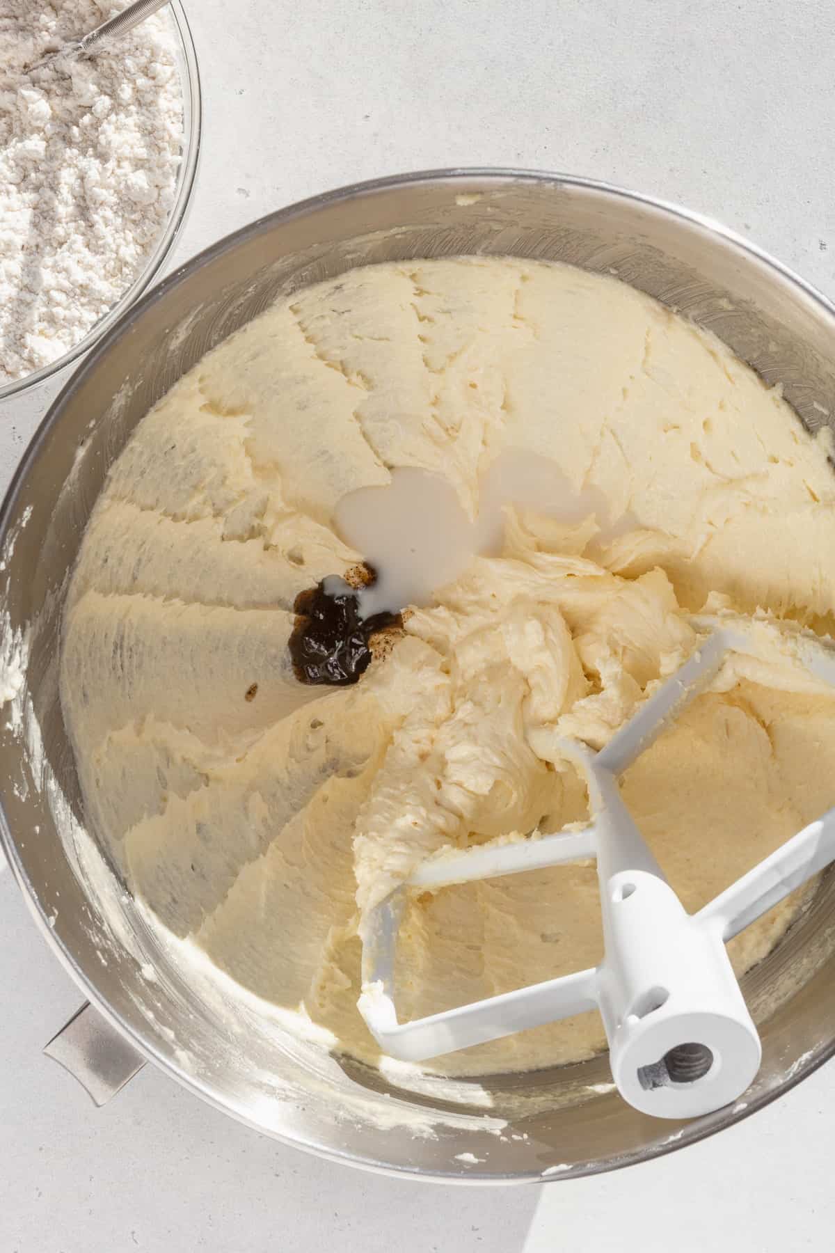 Creamed butter and sugar in the bowl of a stand mixer, with a splash of vanilla extract and milk.