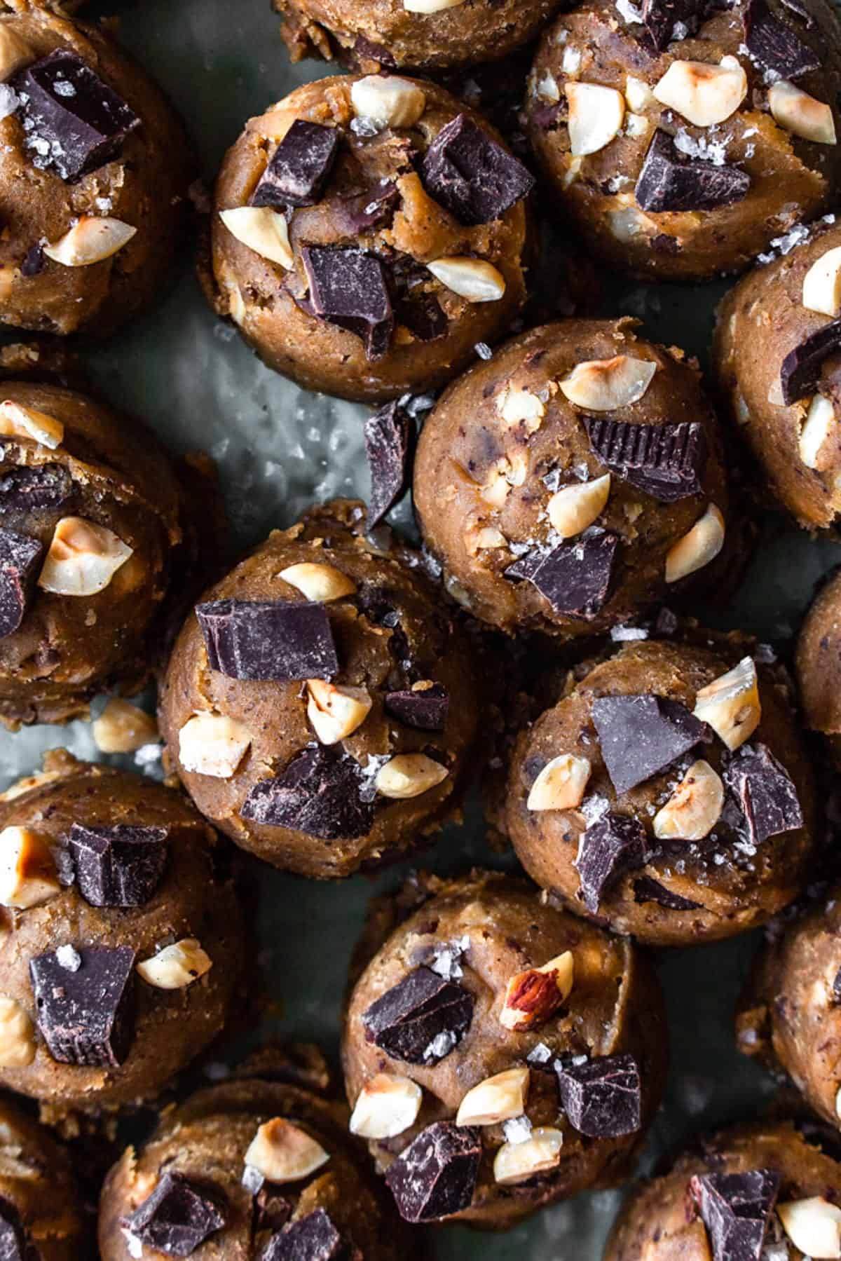 Brown butter cookie dough balls topped with chopped chocolate and hazelnuts.
