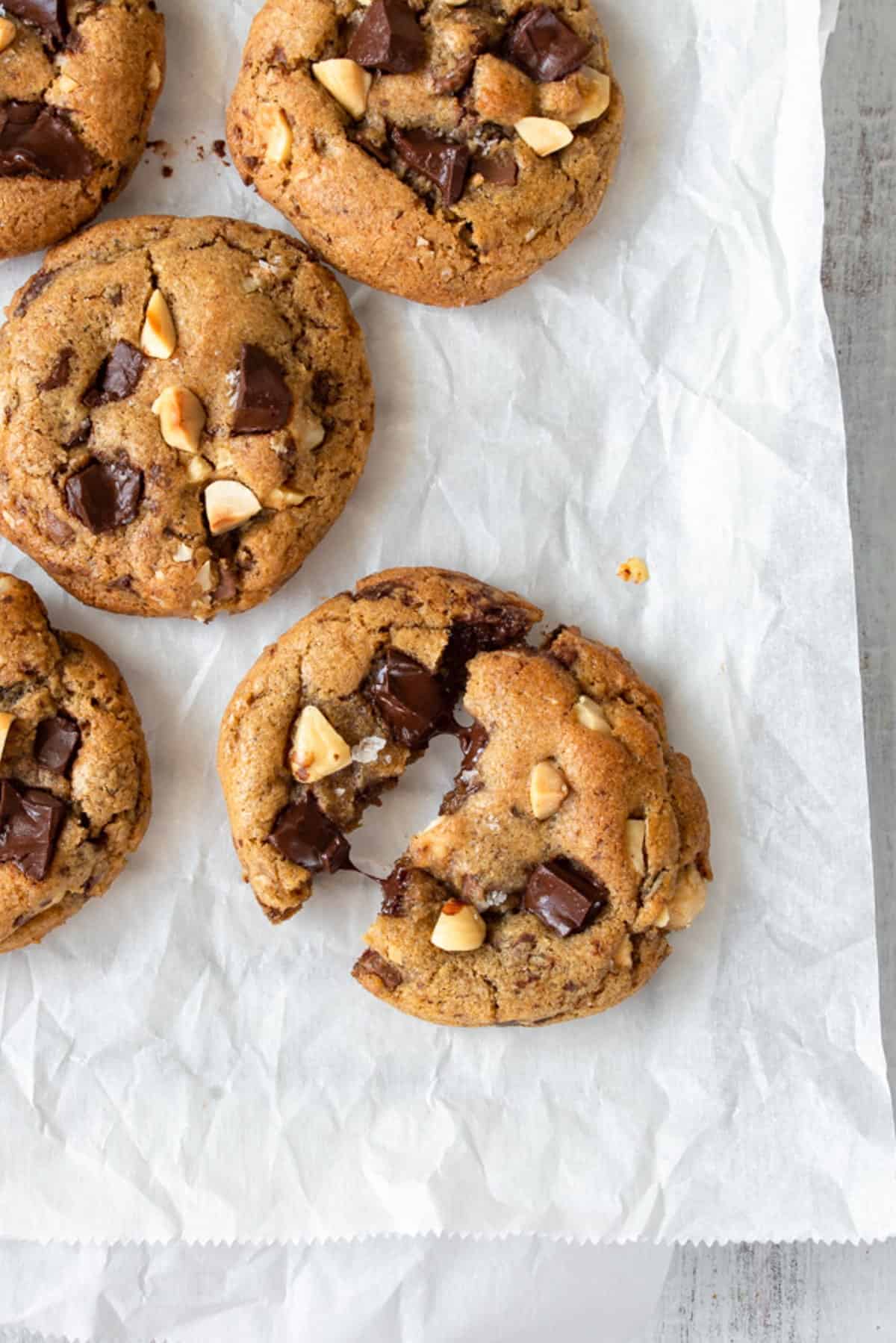 A brown butter cookie broken in half, with more cookies on the side.