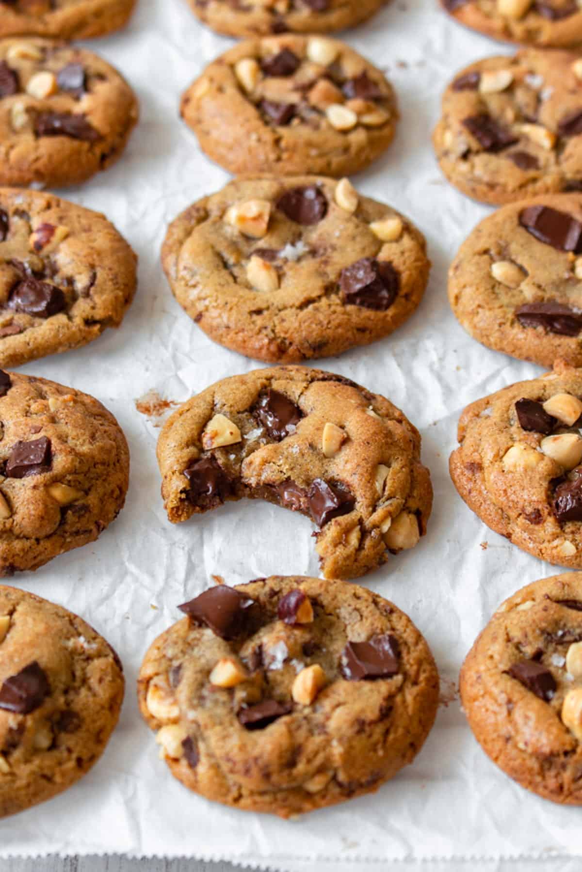 Brown butter chocolate chip cookies laid out in rows, with one having been bitten.
