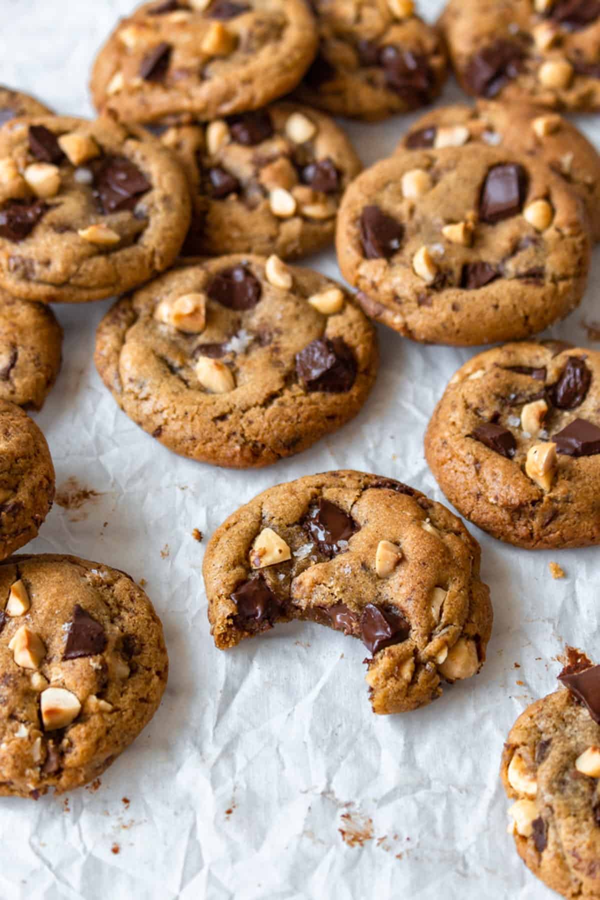 Brown butter chocolate chip cookies scattered on a white surface.