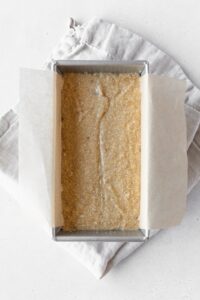 Banana bread batter in a loaf tin on a folded linen napkin.