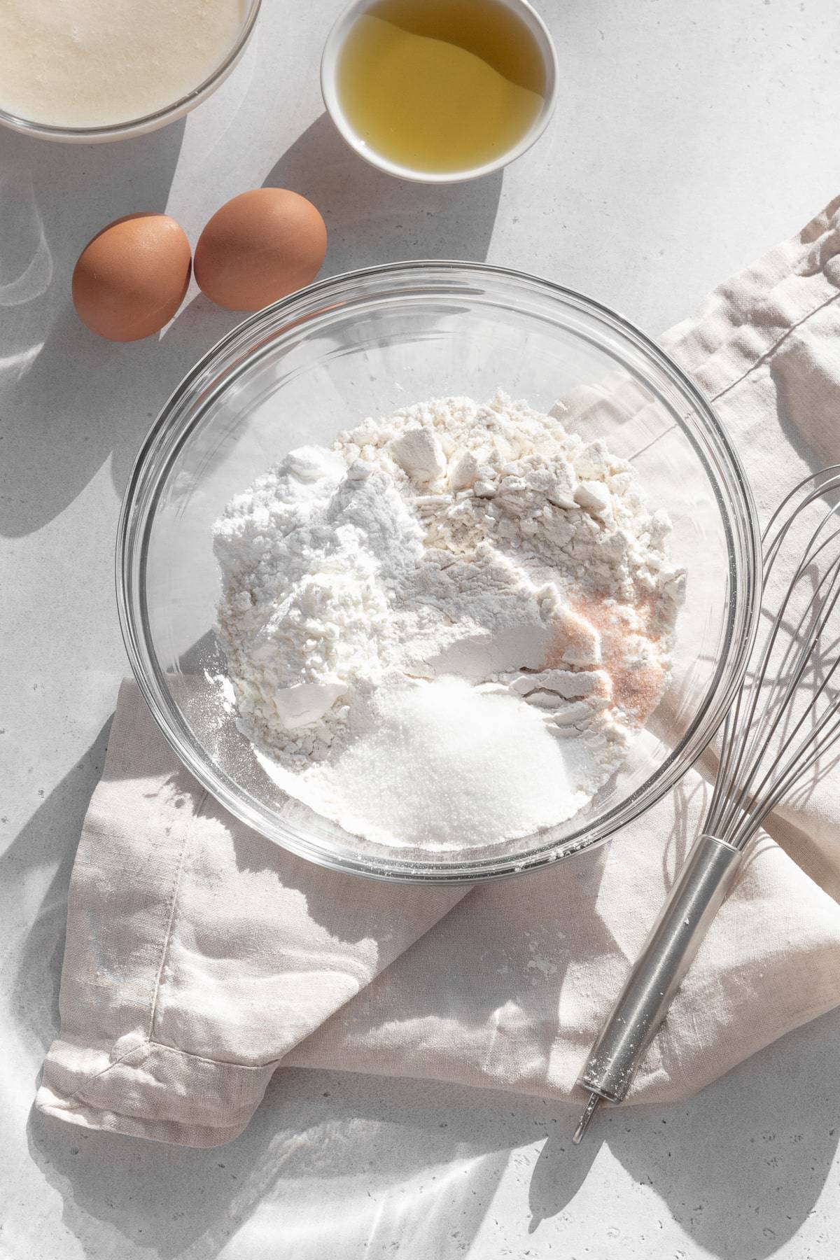 Dry ingredients for homemade waffles in a glass bowl on a natural linen.