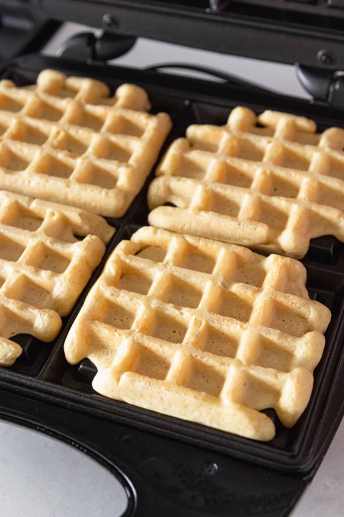 Waffles that have finished cooking on a waffle iron.